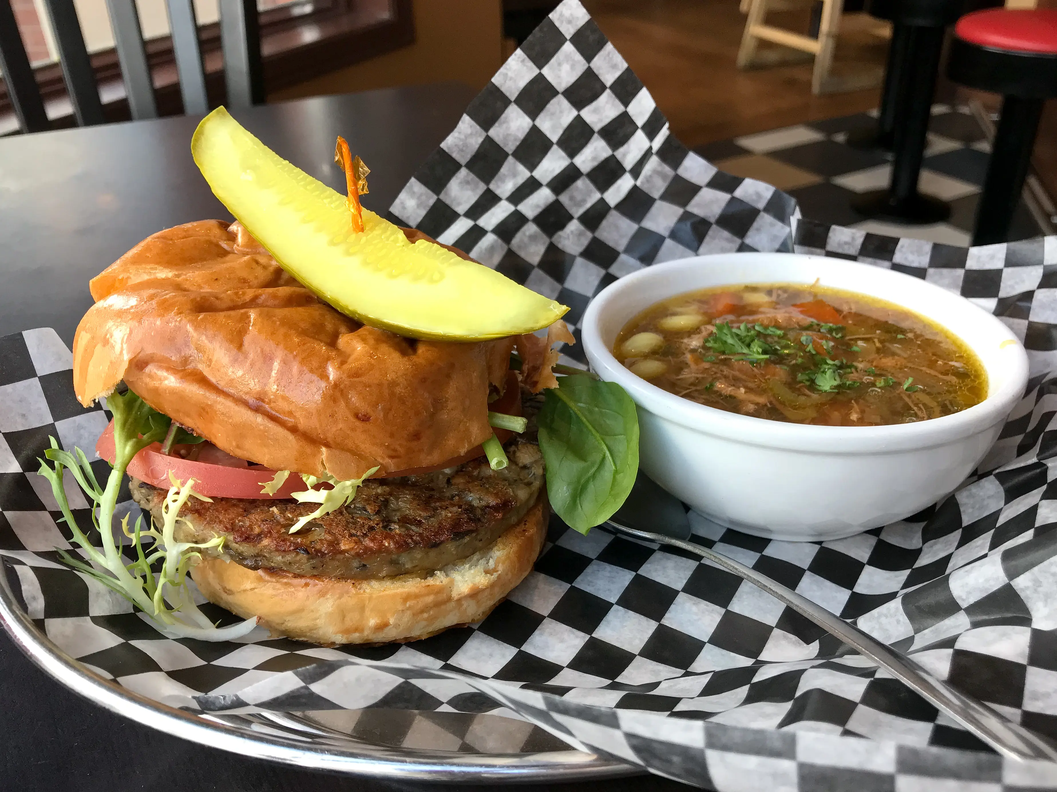 Veggie burger with a pickle spear and a side of chicken noodle soup at Urban Diner in Edmonton, Alberta.