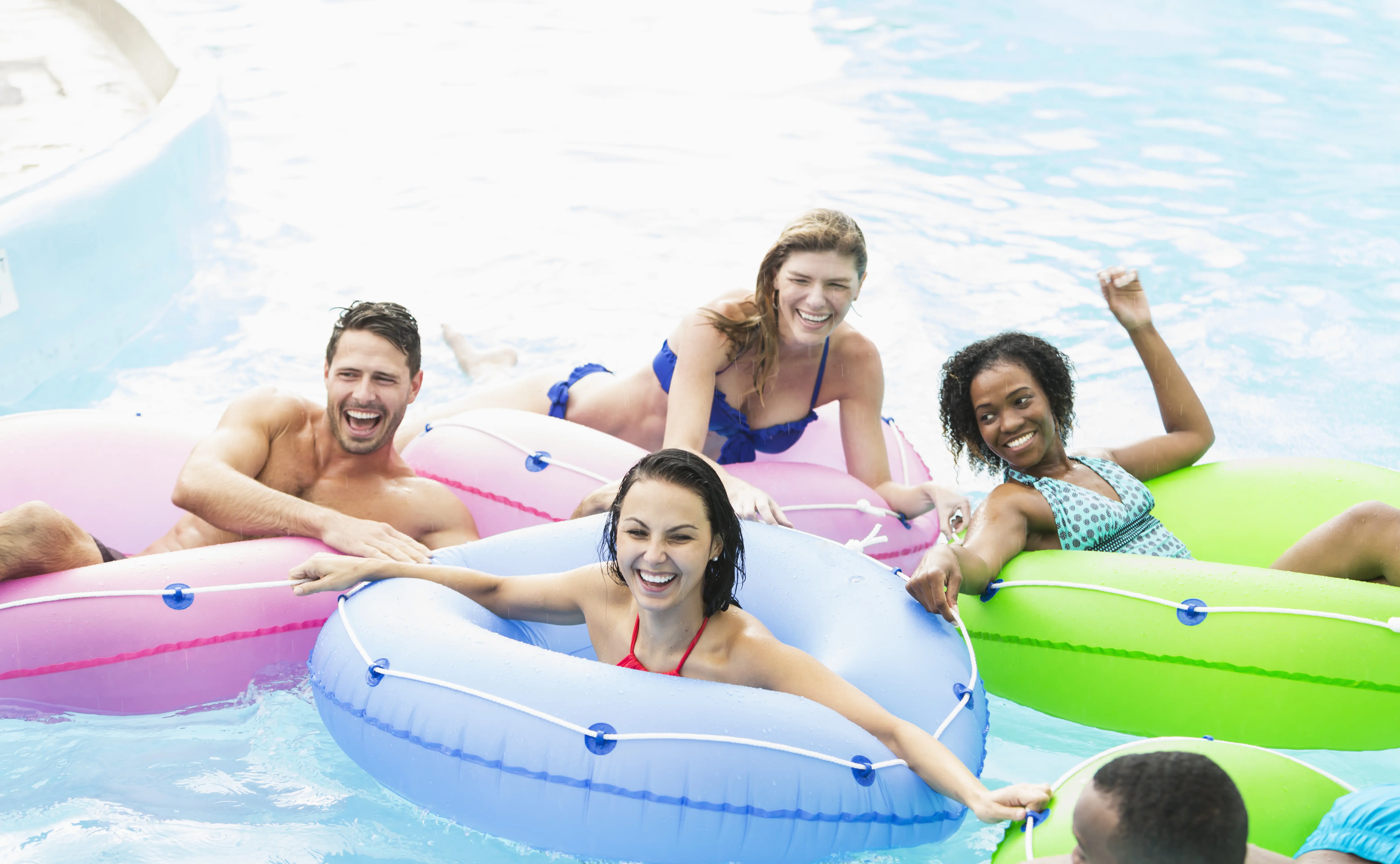 Image of people swimming and relaxing in inflatable tubes on a lazy river.