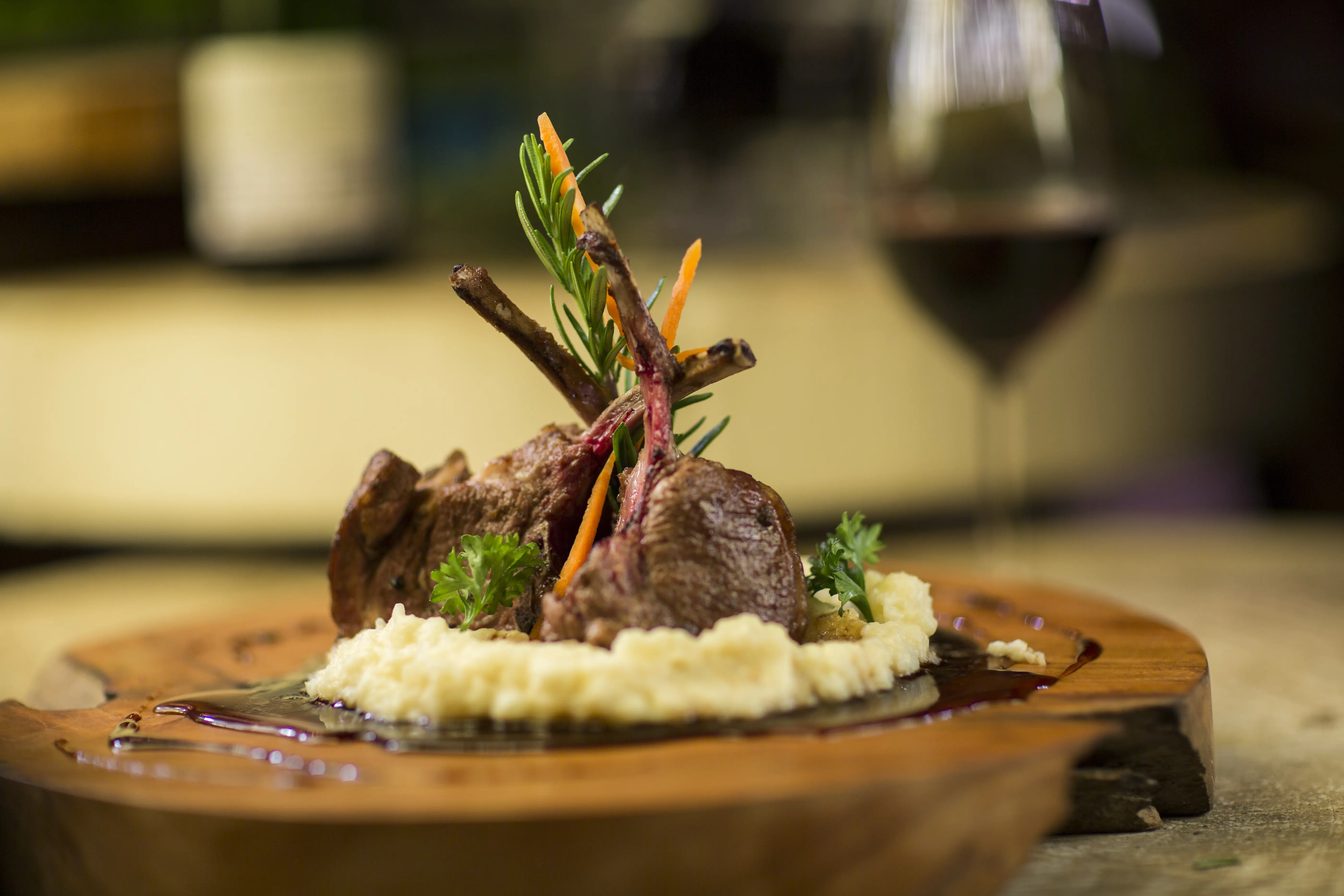 Image of a finely prepared serving of lamb chops on a wooden board.