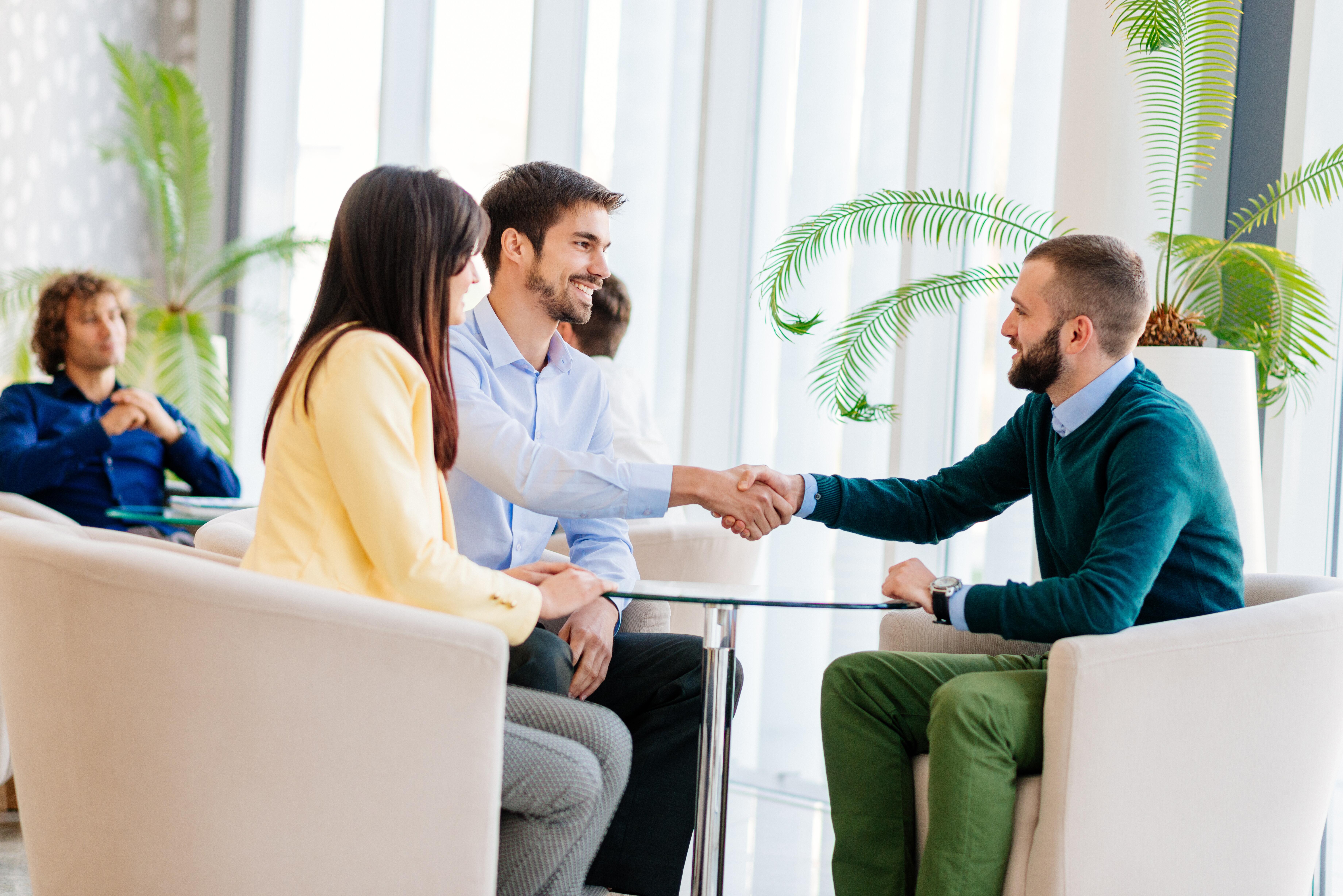 Image of a man shaking another man's hand at a meeting.