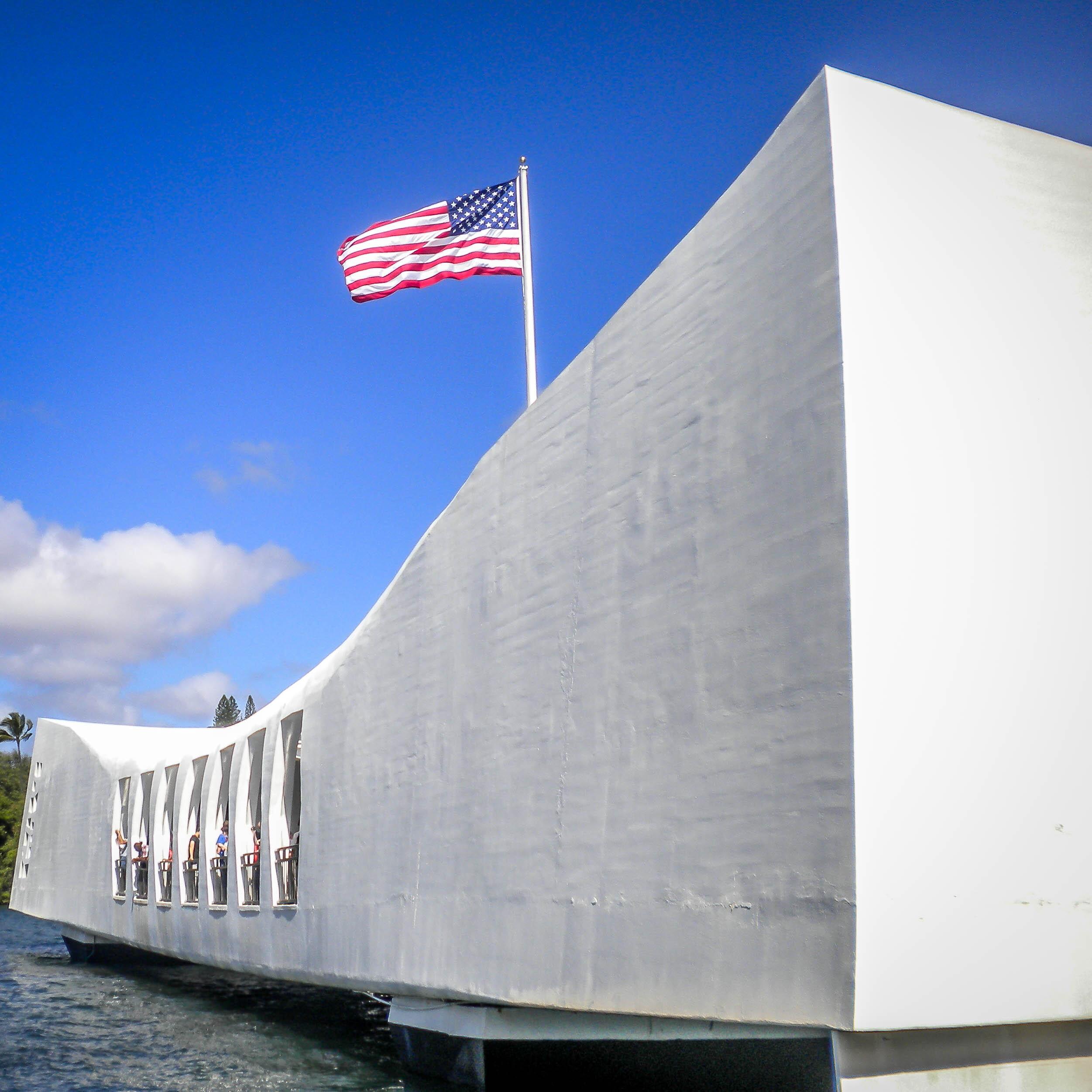 Exterior of USS Arizona Memorial with an American flag in the Pearl Harbor National Memorial.