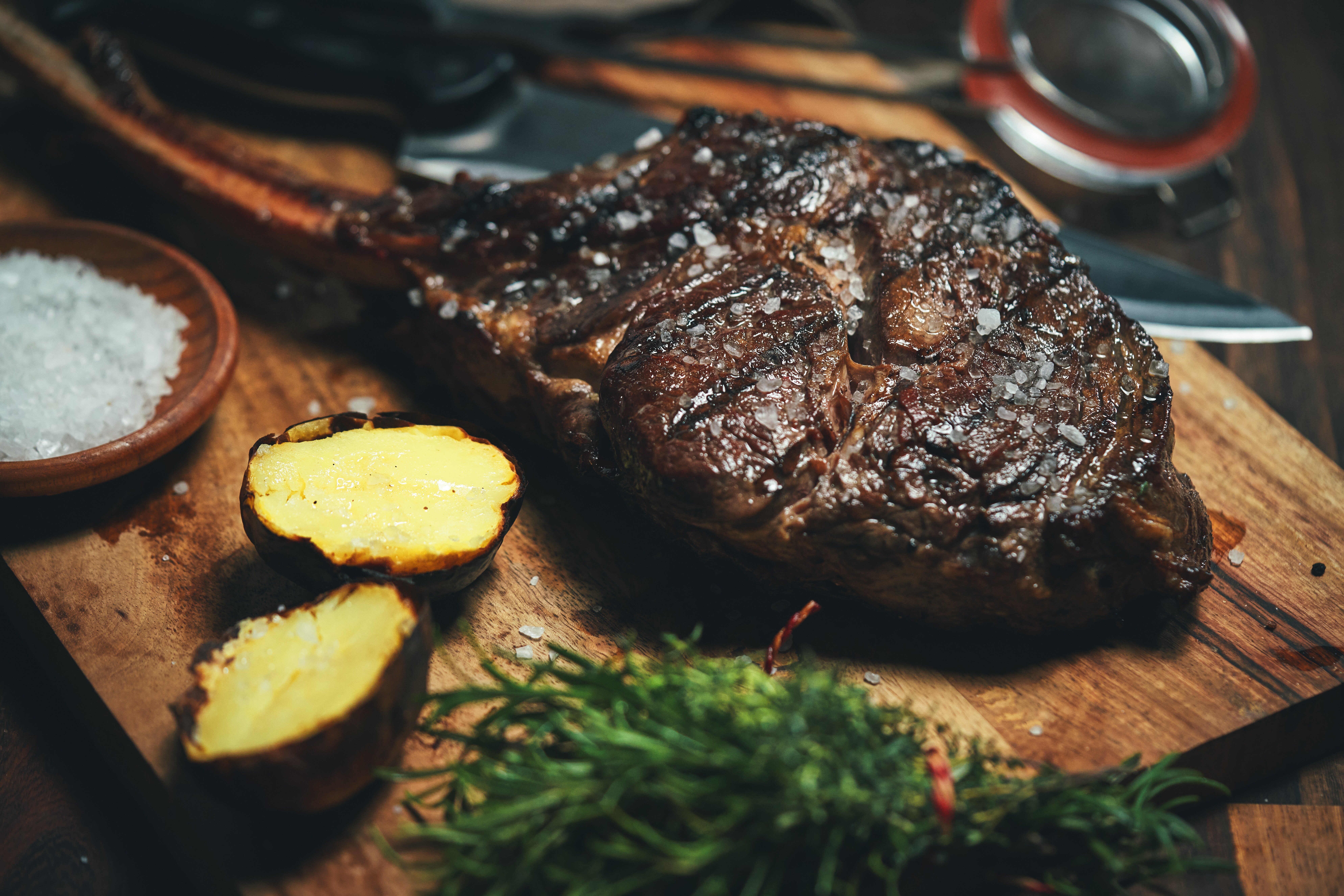 Closeup image of a tomahawk steak on a wooden cutting board.