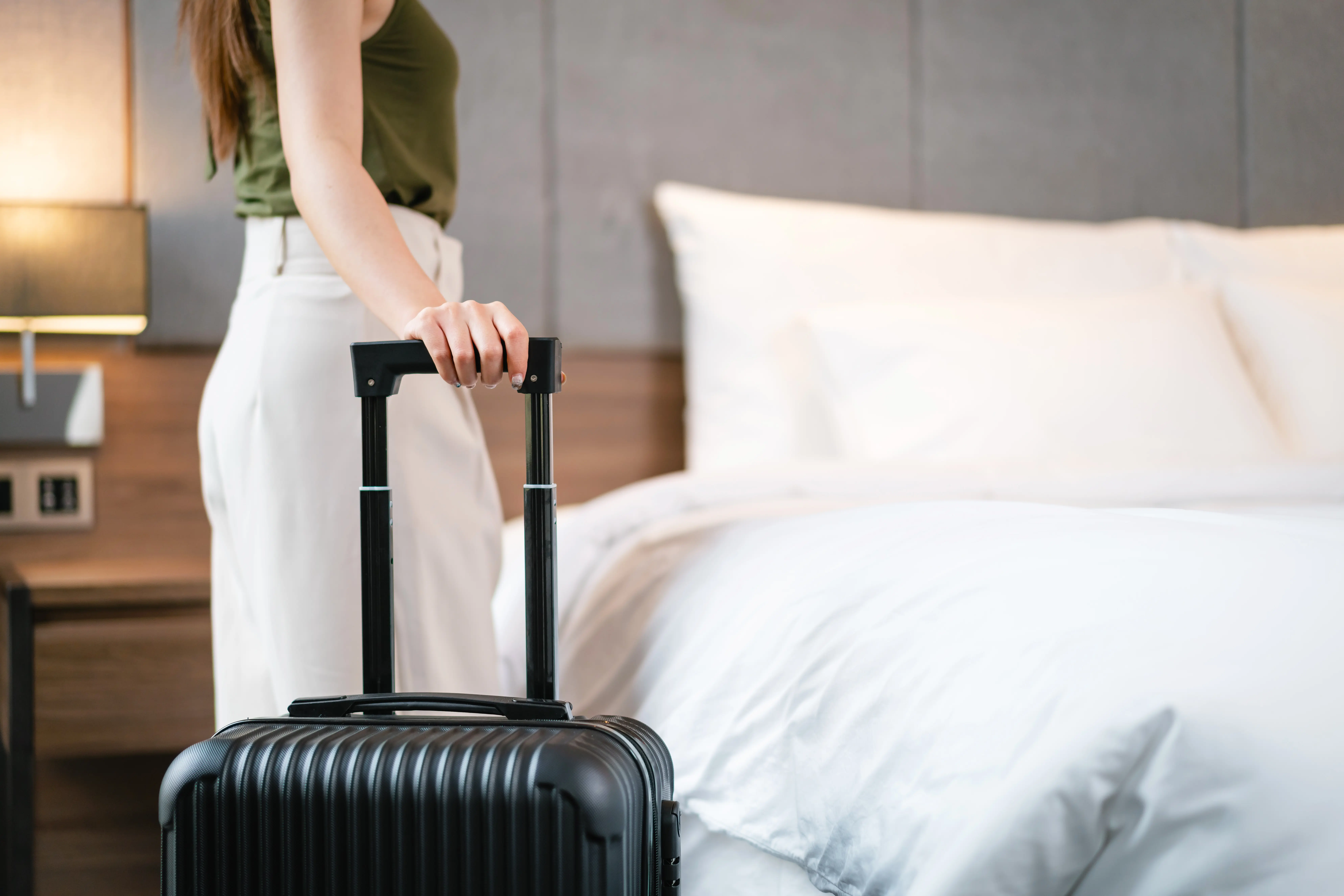 Young woman standing with suitcase in hotel room