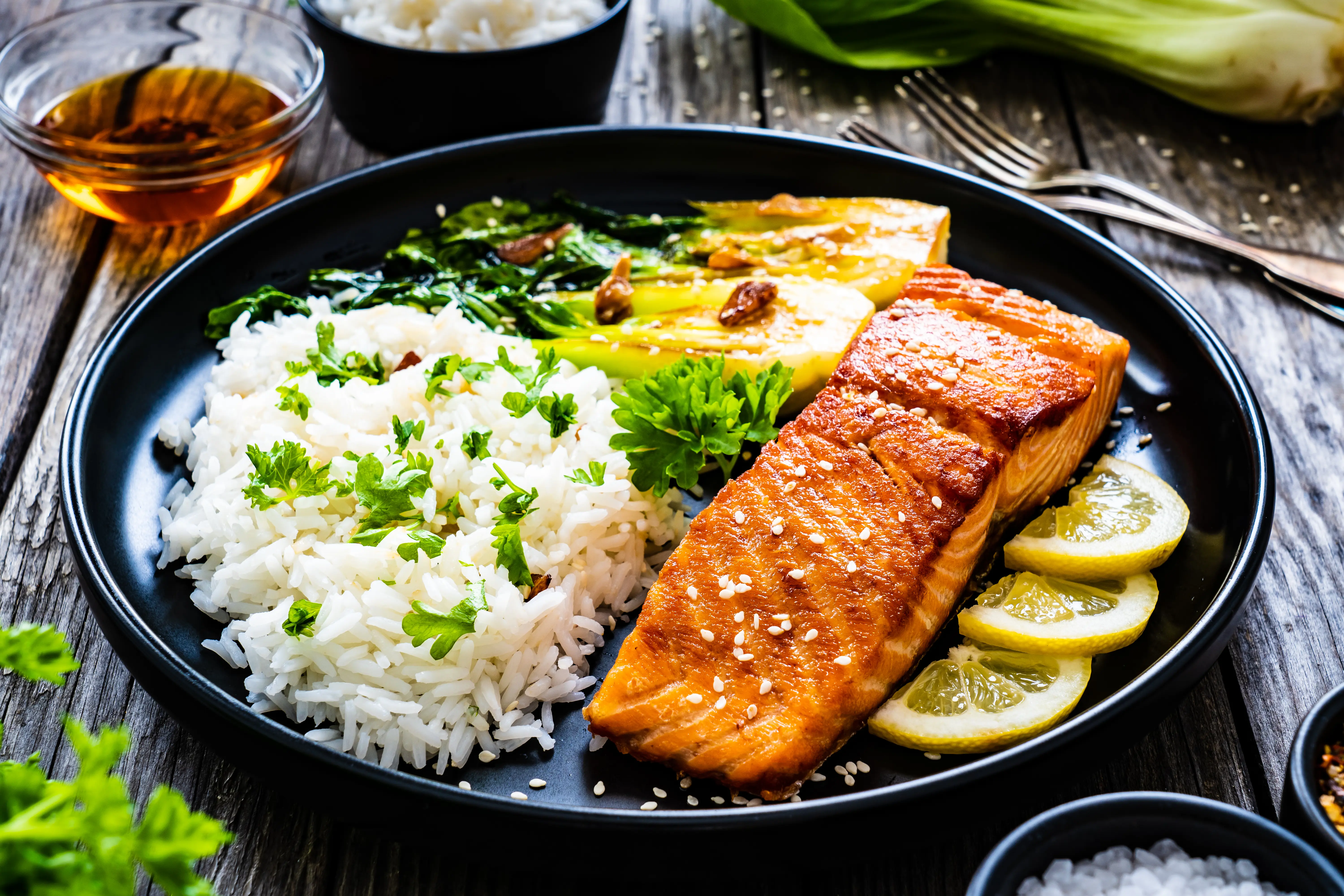 Salmon steak with pak choi cabbage and jasmine rice on wooden table