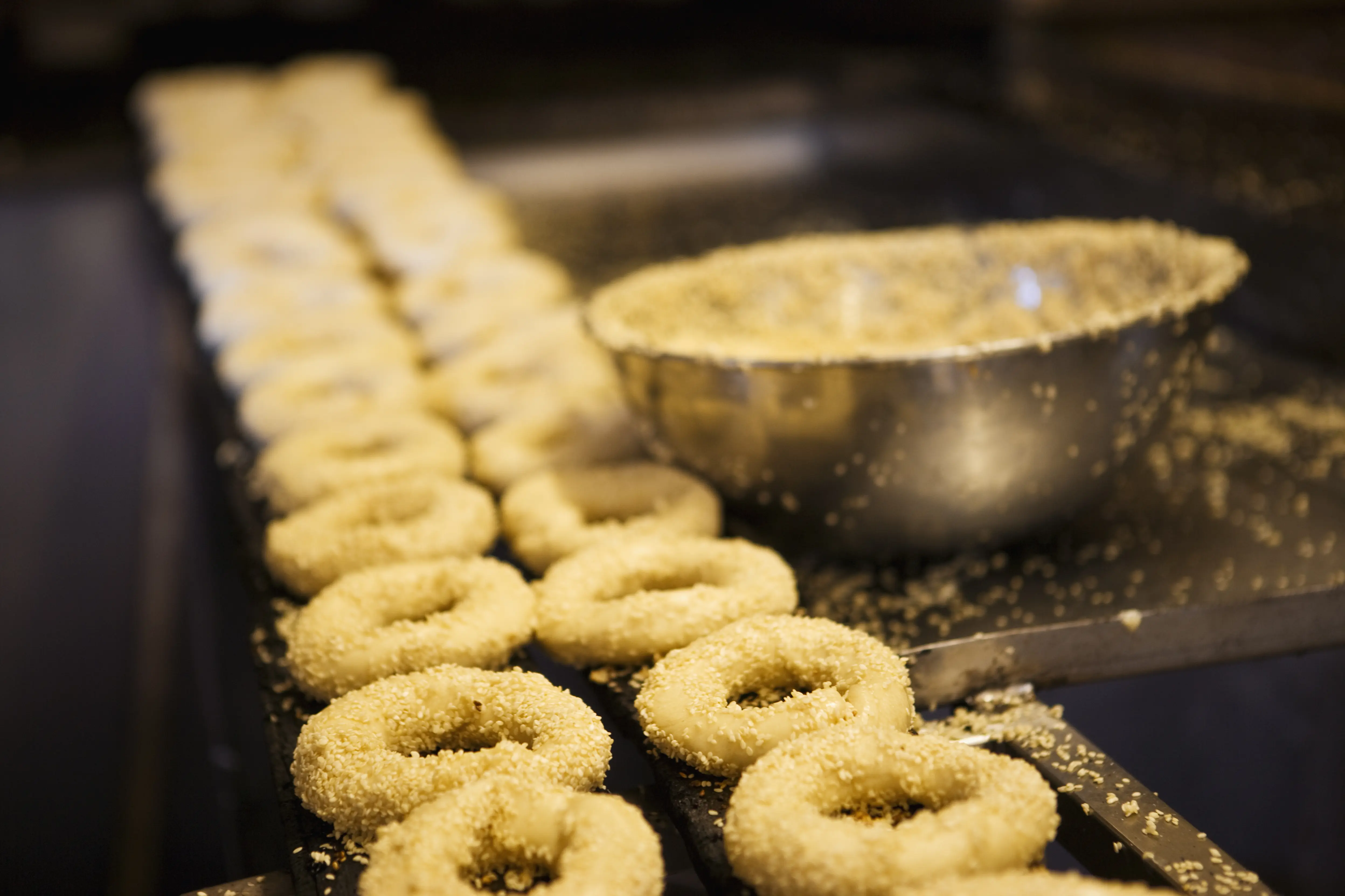 Image of uncooked bagels on an assembly line.