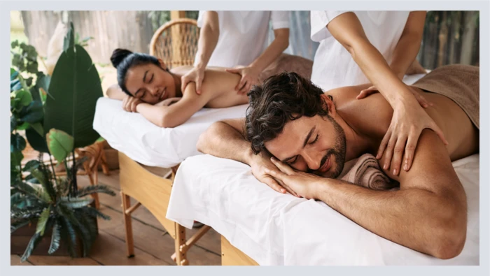 A couple lays on outdoor massage tables while getting massages. 