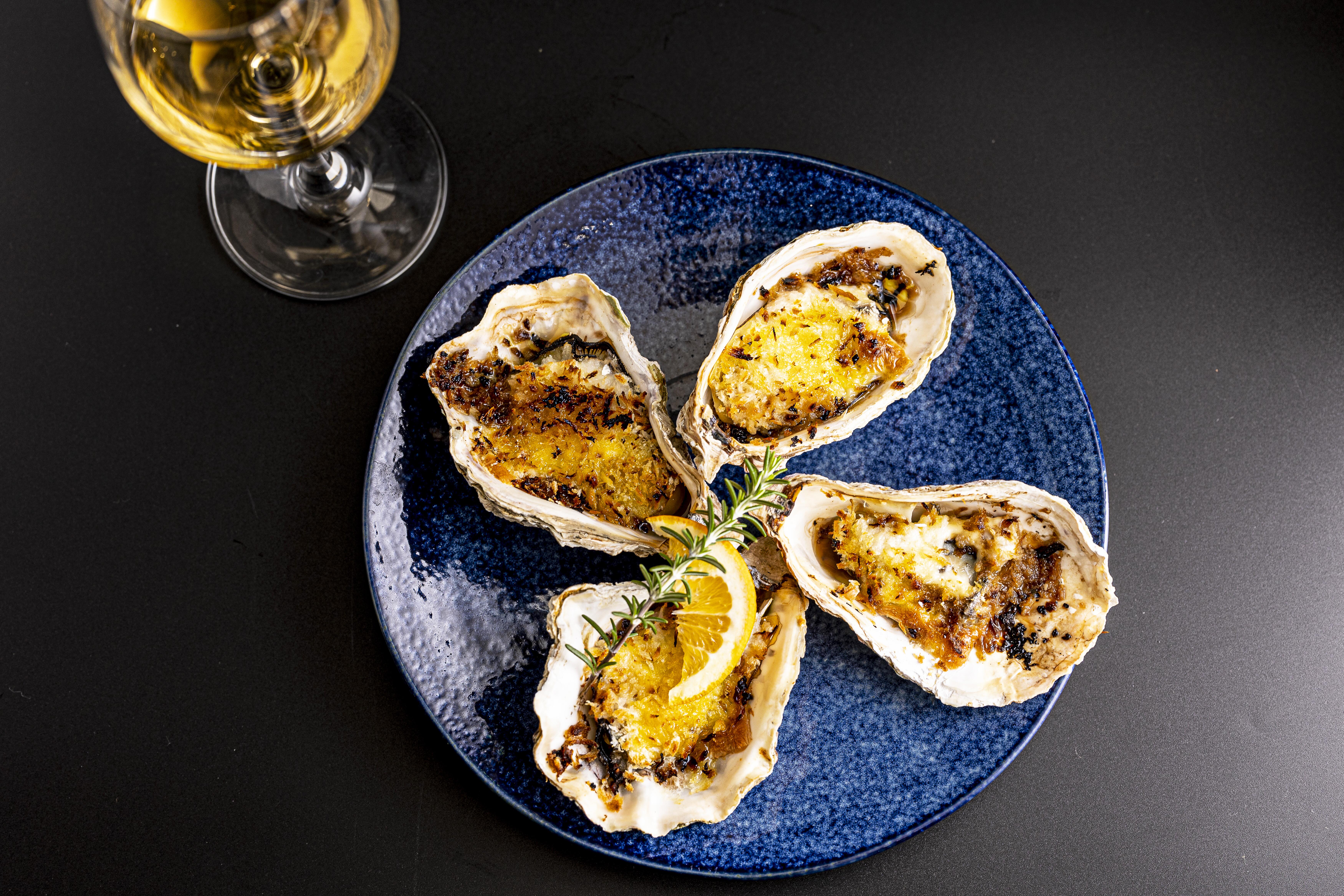 Oysters on a blue plate next to a glass of white wine