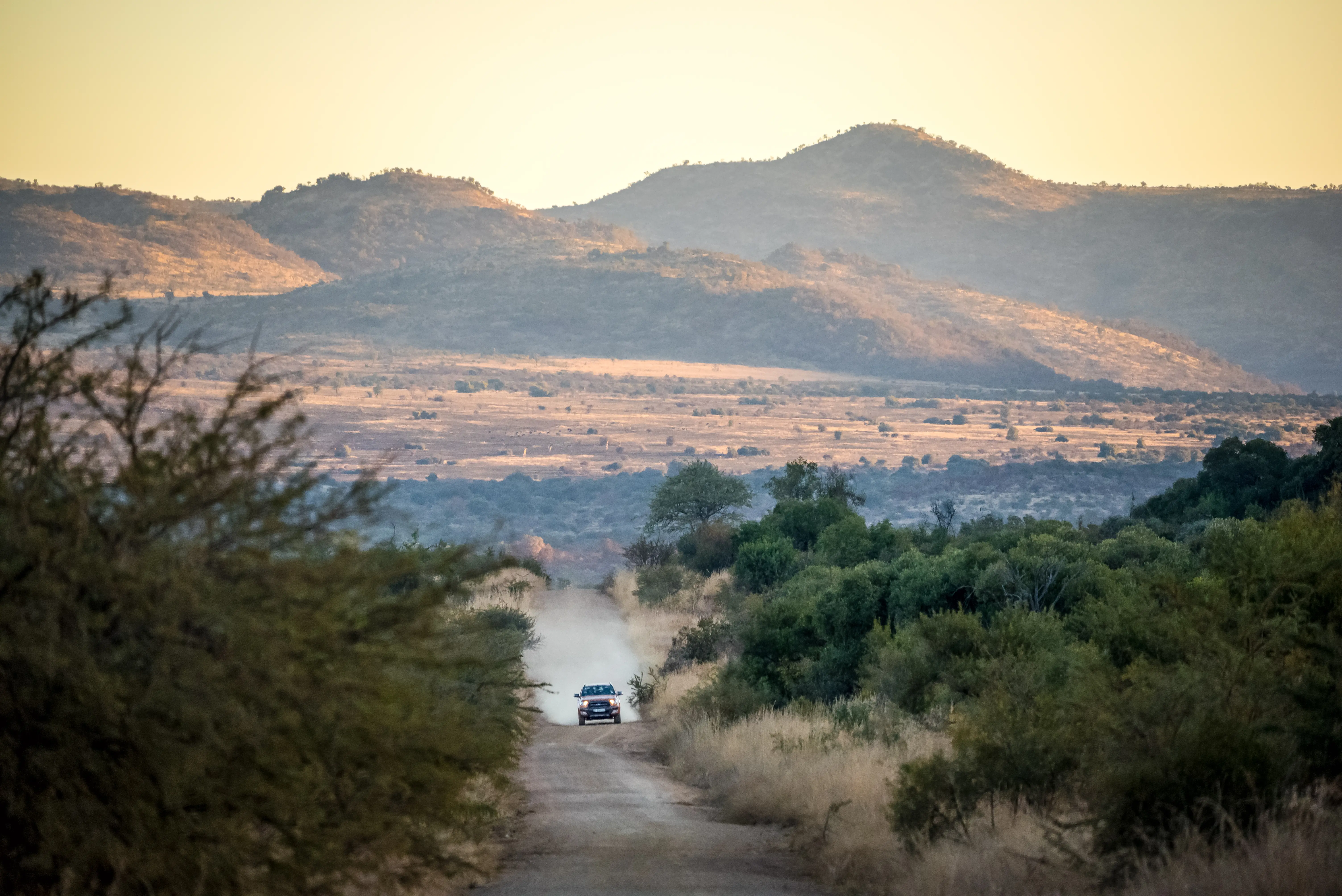 Image of a car driving on a dirt road at Pilanesberg Game Reserve, located north of Rustenburg in North West Province in South Africa.