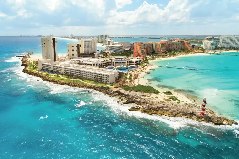 Birds-eye view of the Hyatt Ziva Cancun with waves crashing against a rocky shoreline.