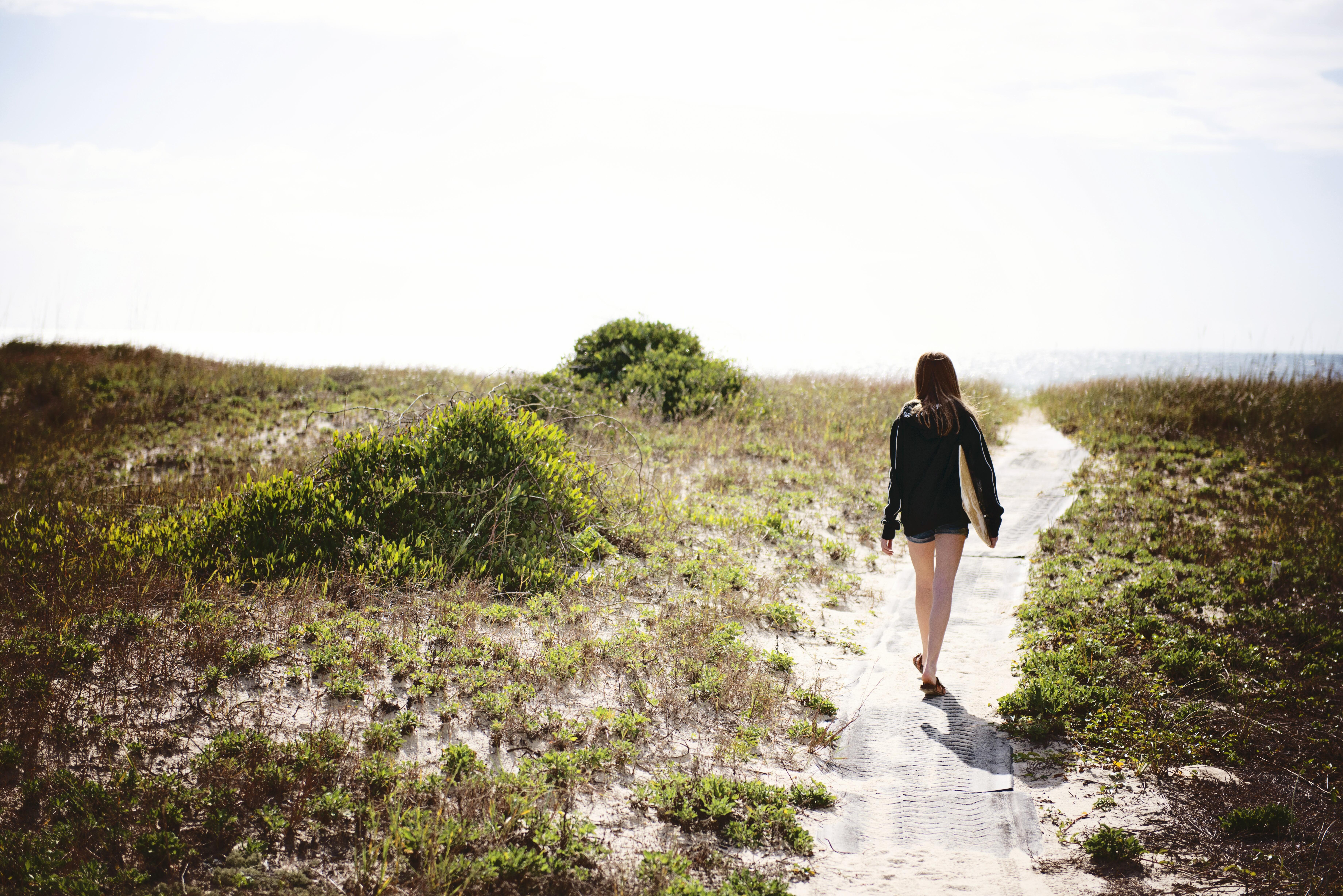 Image of a woman walking among the sand dunes and shore of St. George Island, Florida.