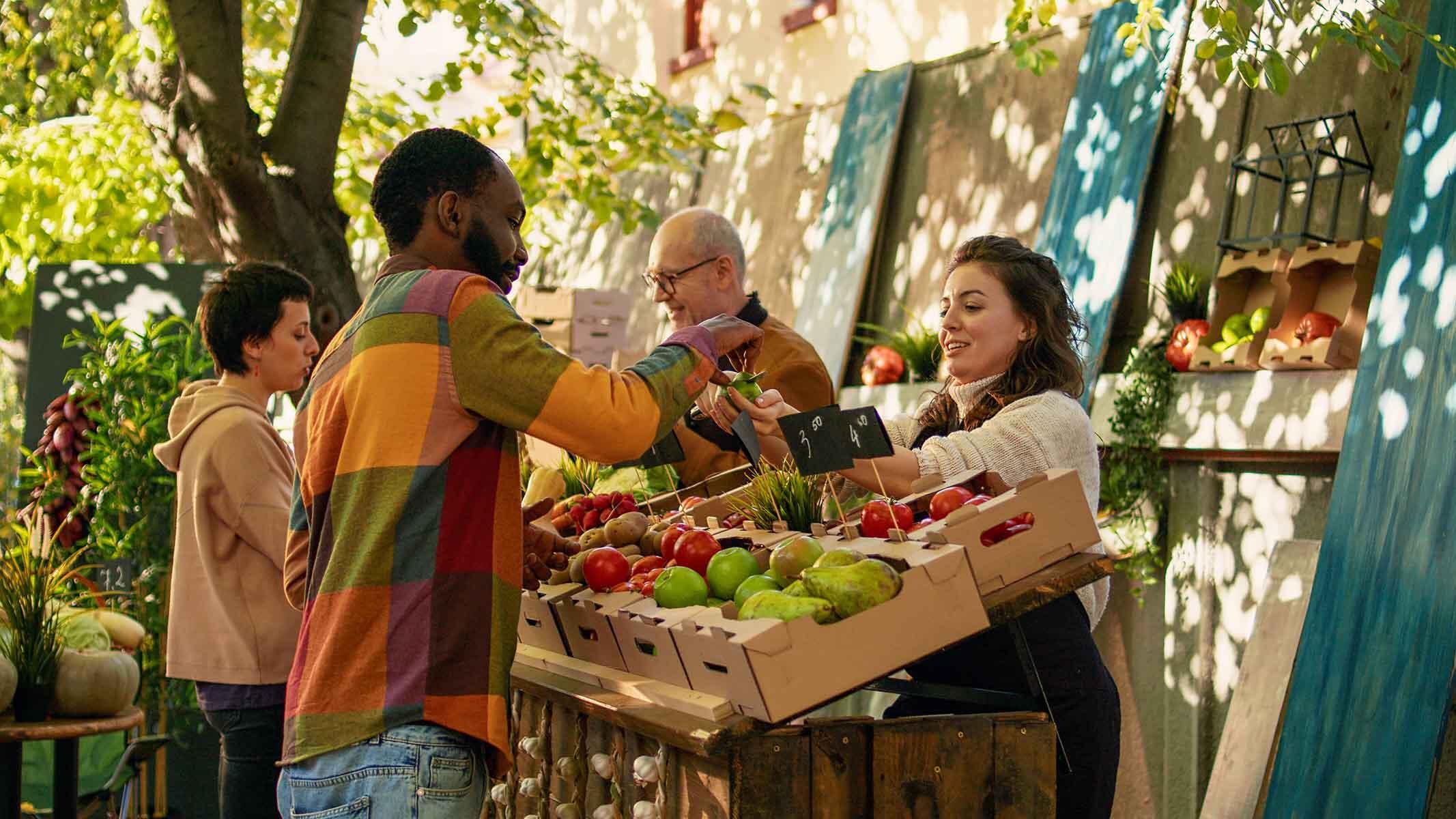 People purchasing fresh produce from a vendor in the Portland Farmers Market