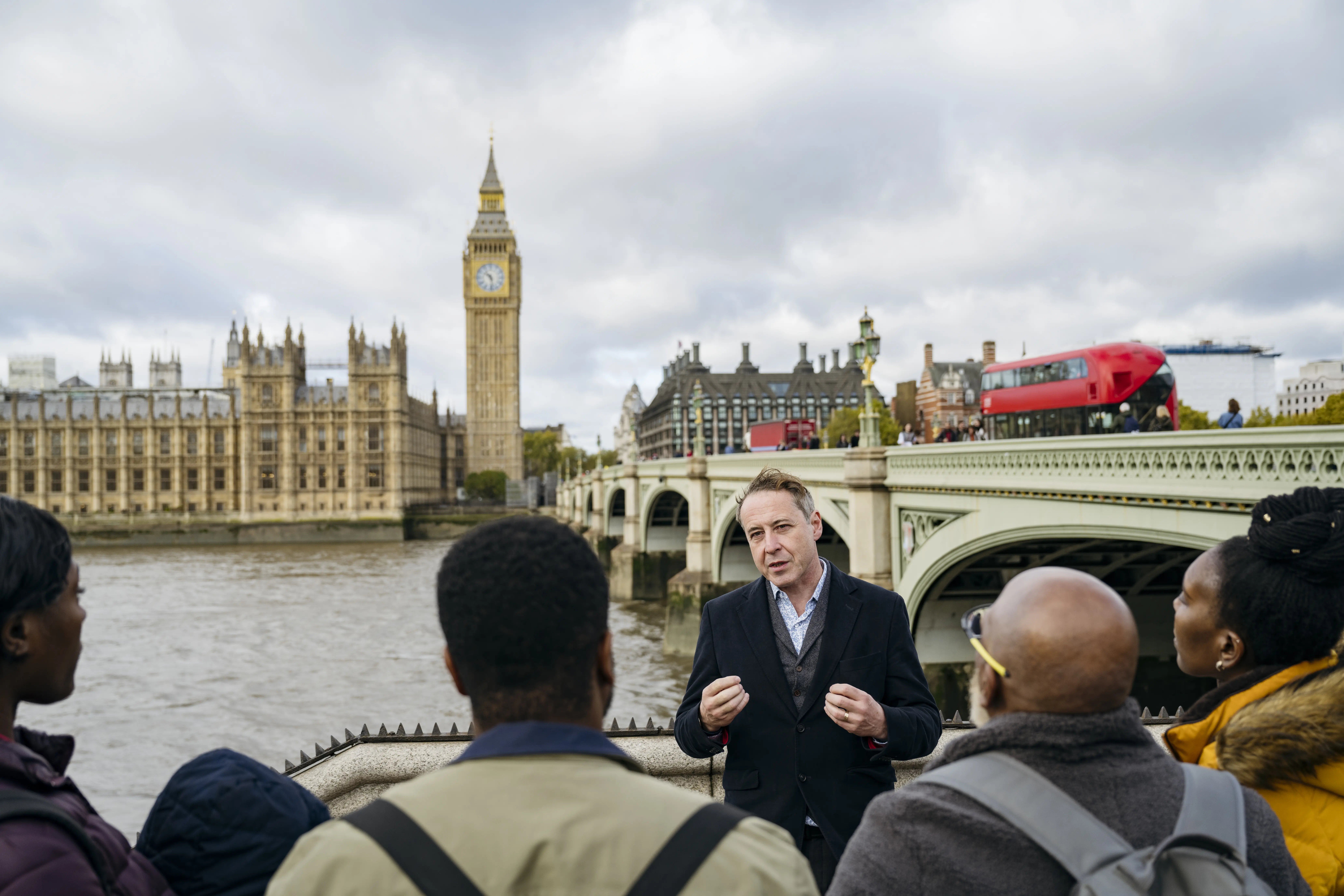 Image of a tour guide in London, with the River Thames and Big Ben in the background.