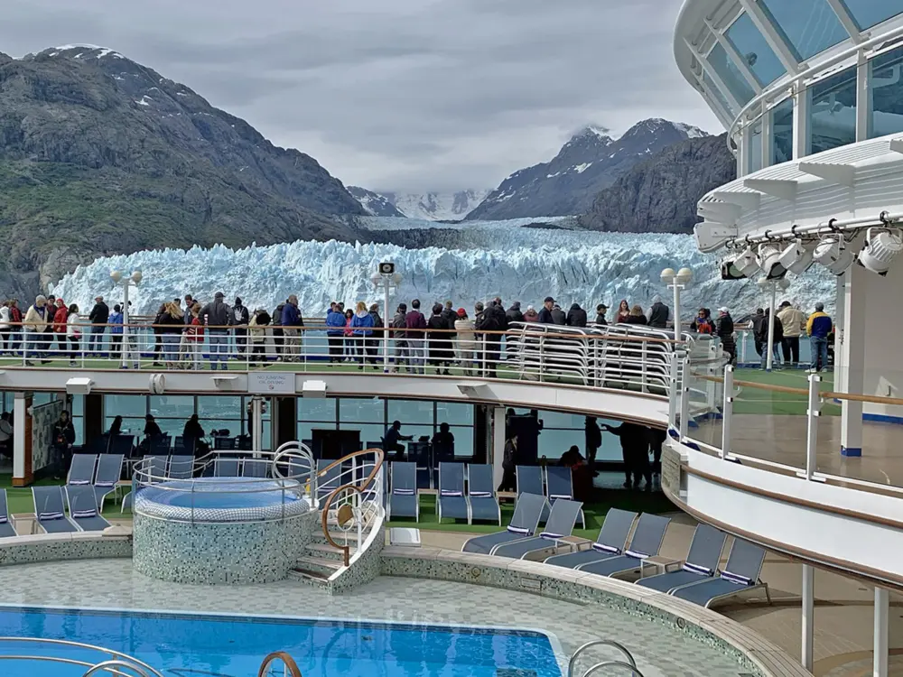 Passengers aboard a cruise ship off the coast of Alaska view a glacier.