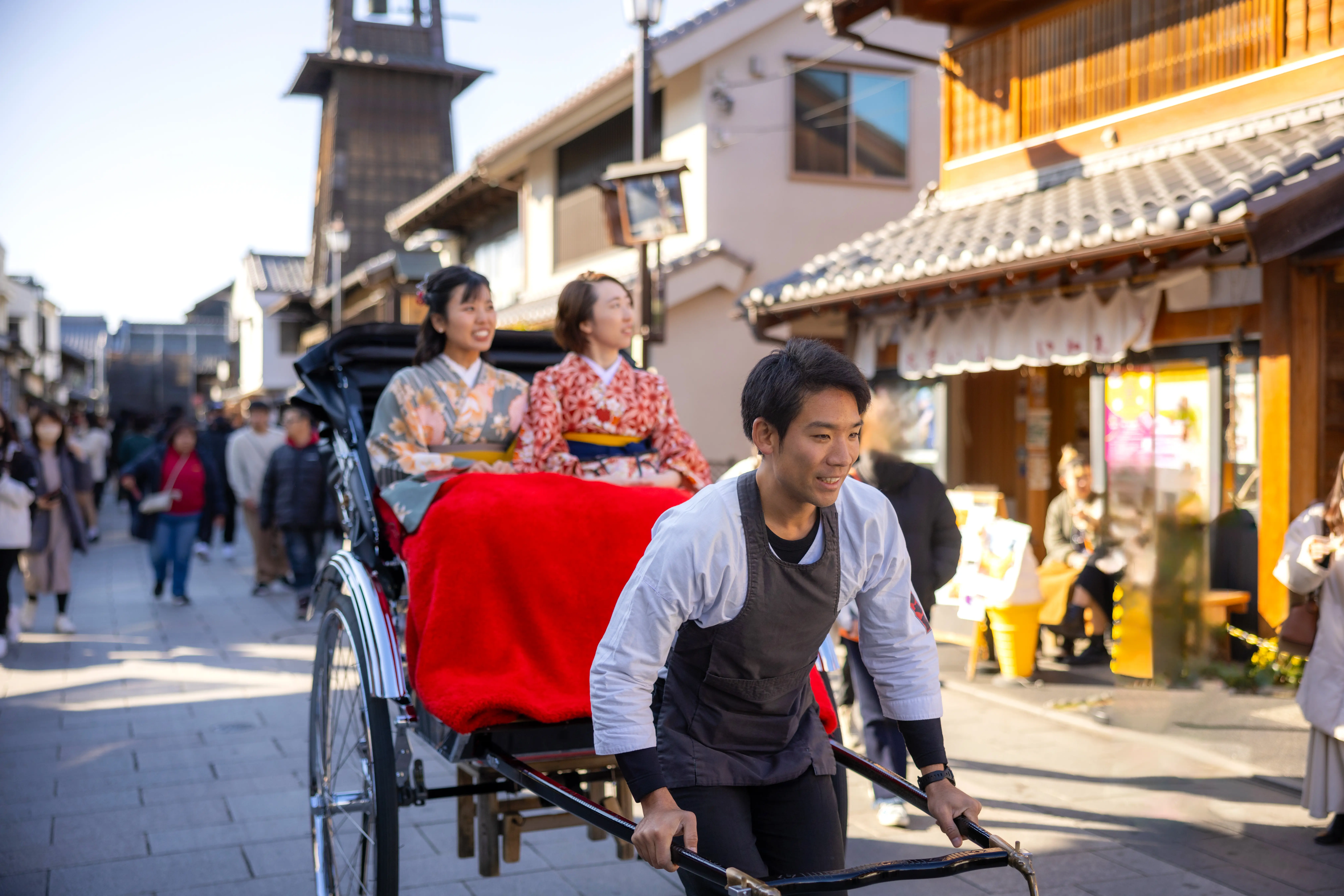 Female tourists dressed in kimonos riding jinkirisha rickshaw