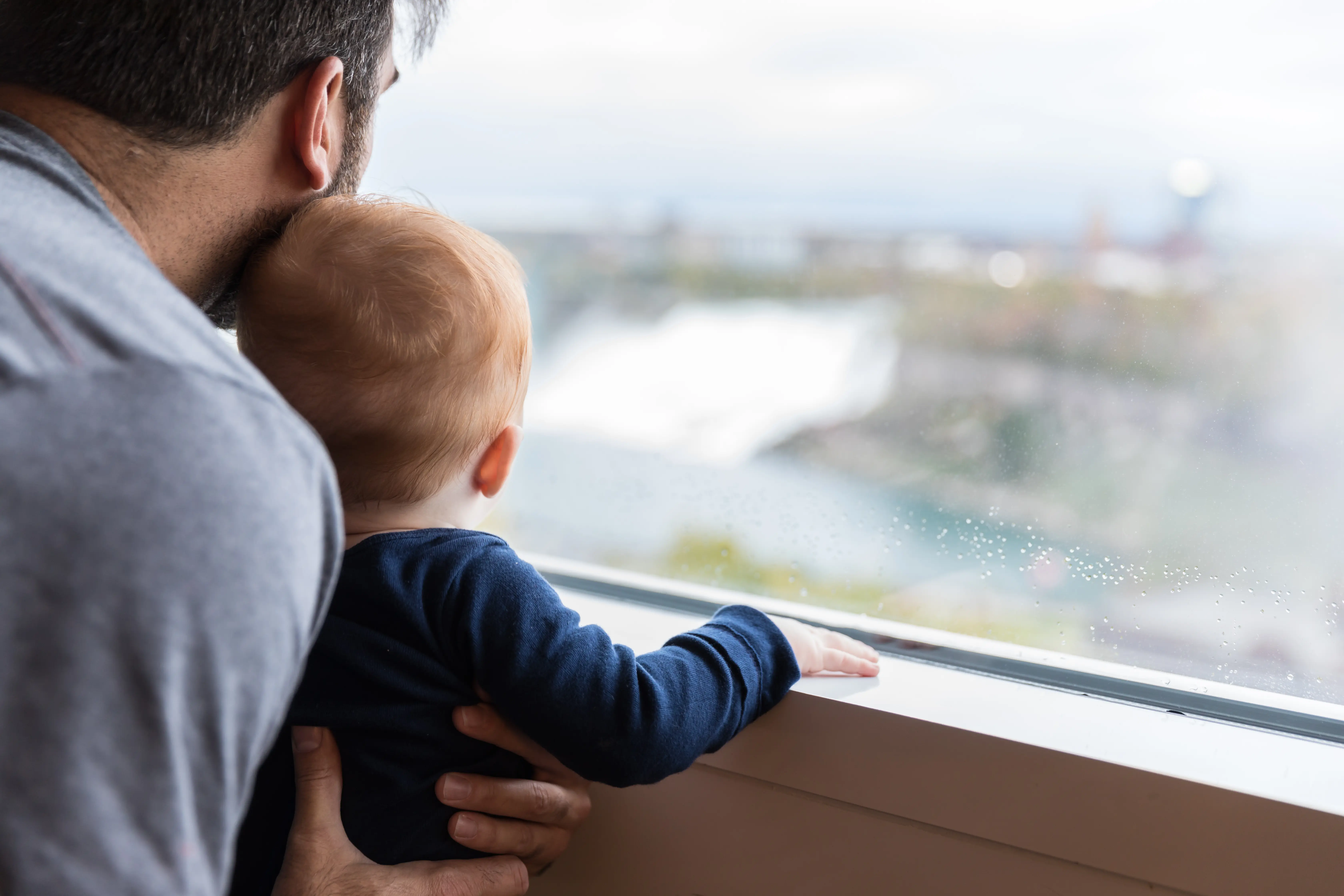 Dad showing his baby boy the famous Niagara Falls from an inside window