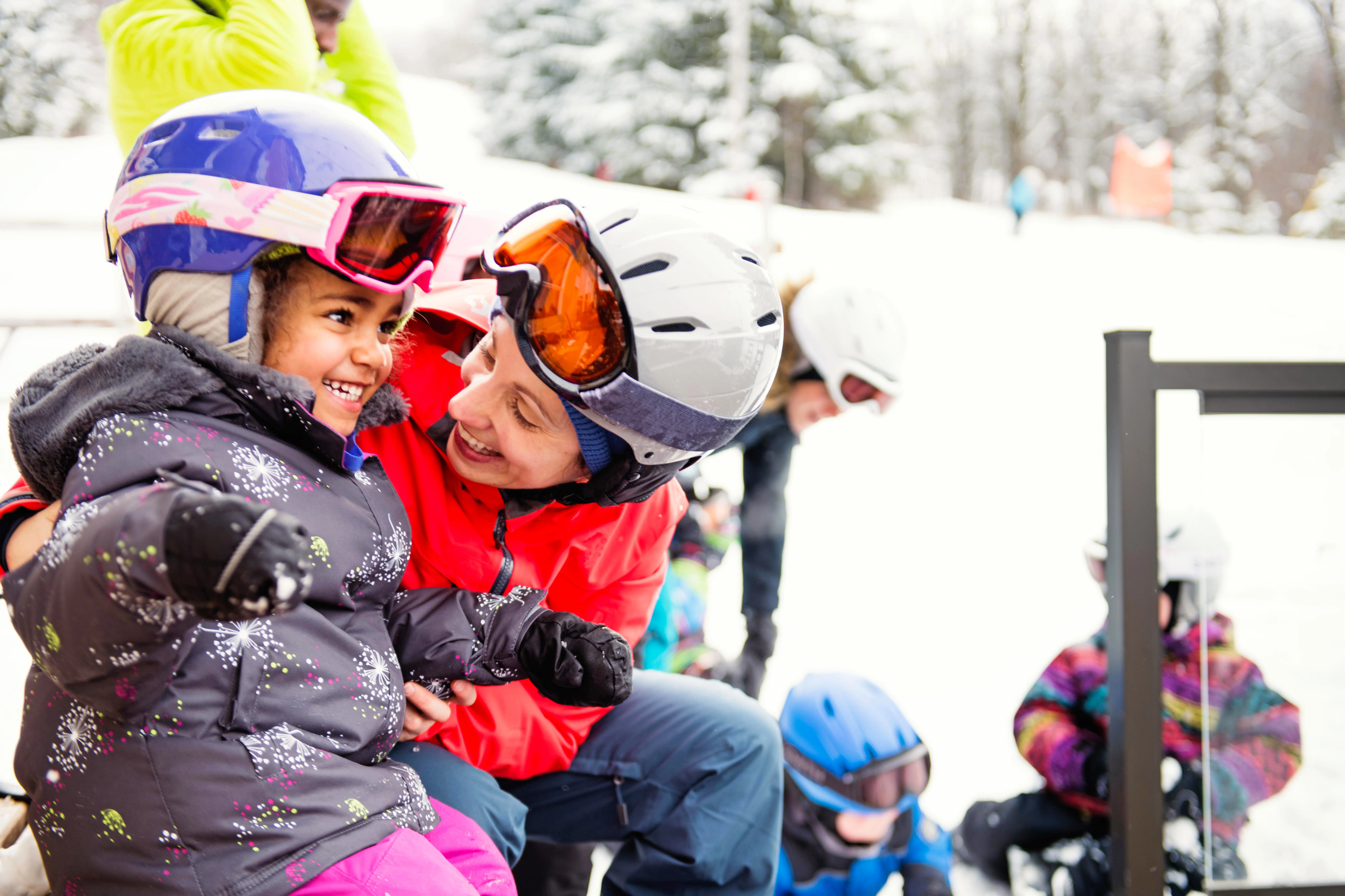 Mother and young daughter excited to go skiing at a ski resort