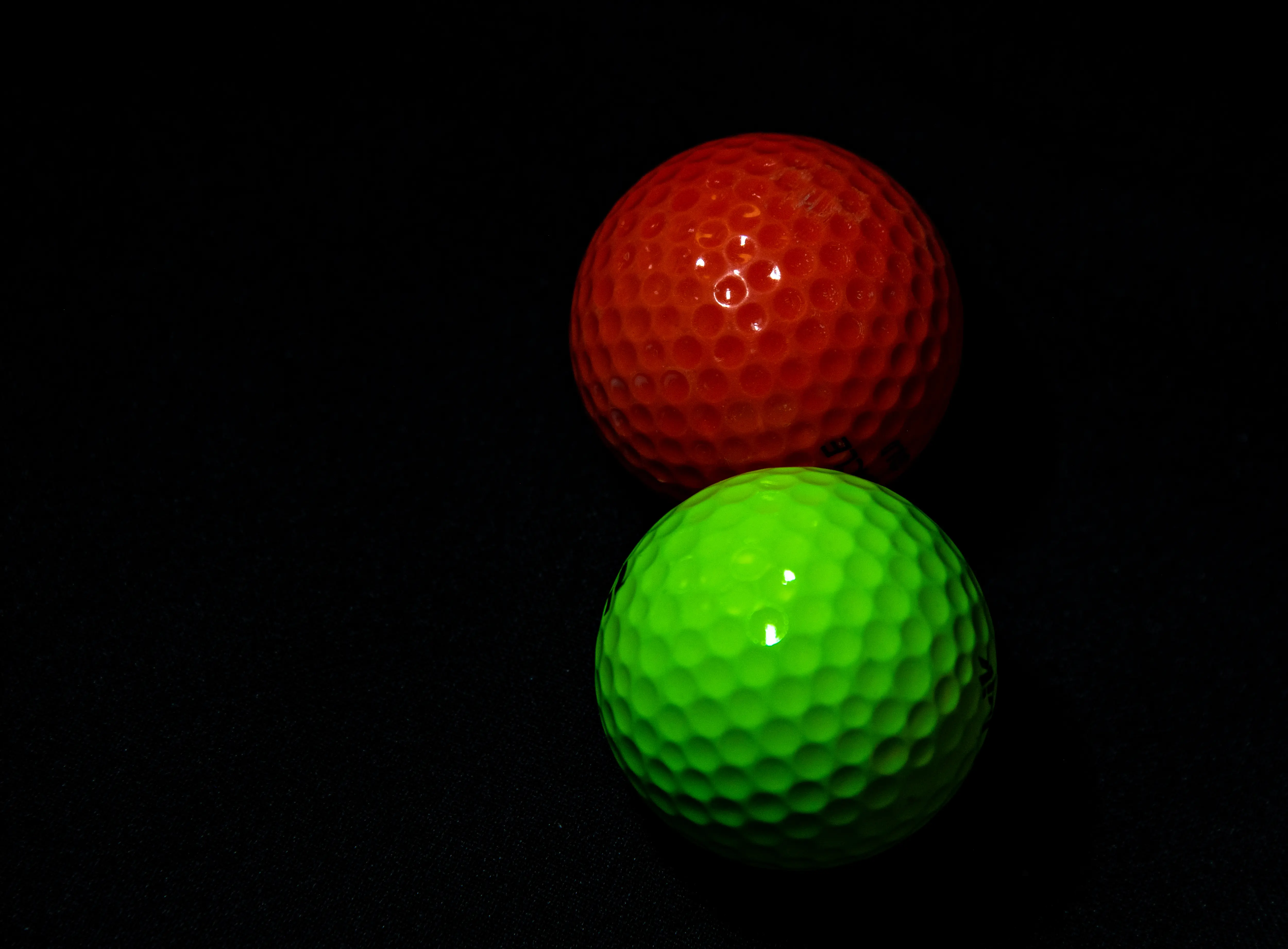 Dark image of two mini golf balls, glowing.