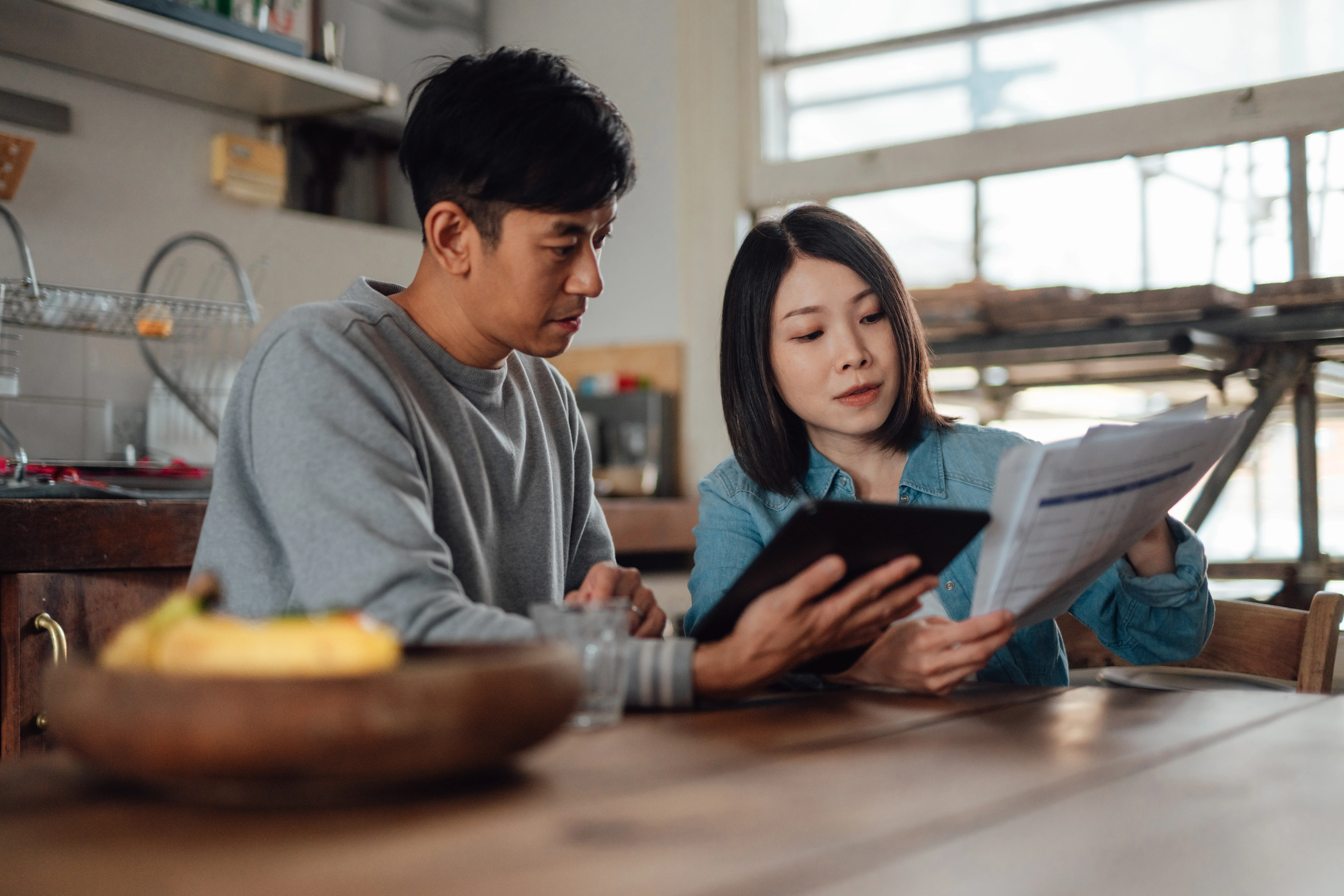 Image of a couple sitting together in a kitchen going over legal documents.