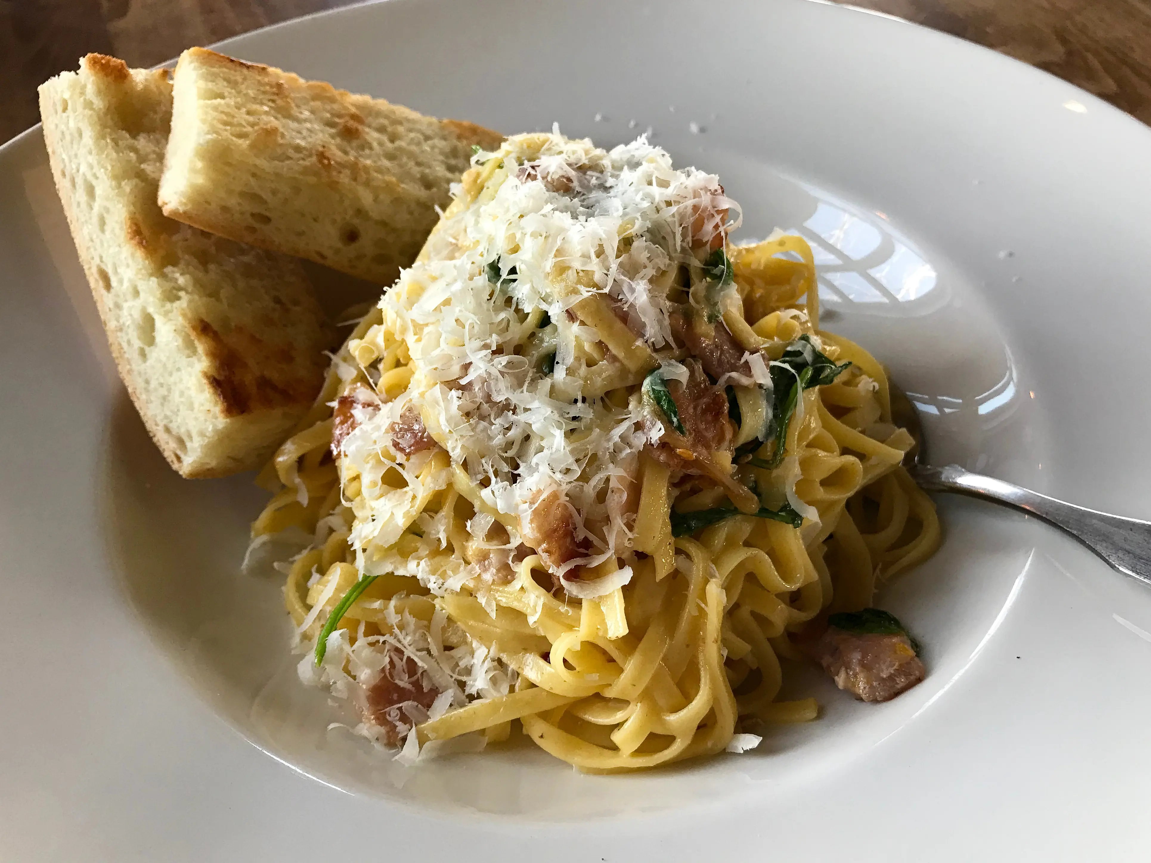 Bowl of carbonara pasta with garlic bread at Cibo Waterfront Cafe in Winnipeg, Manitoba.