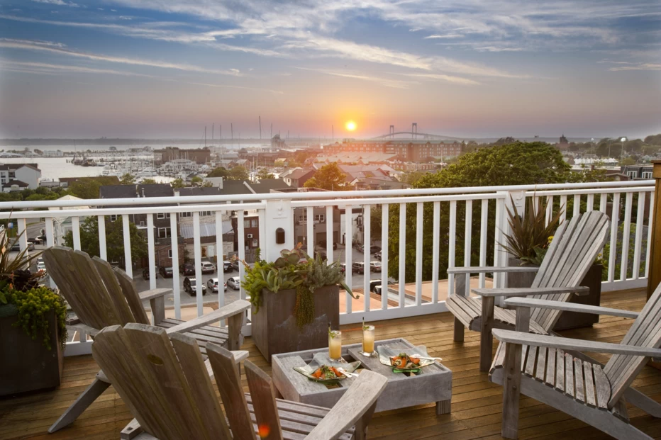 Adirondack chairs on a deck with a sunset view at The Vanderbilt Auberge Resorts Collection hotel in Newport, Rhode Island.