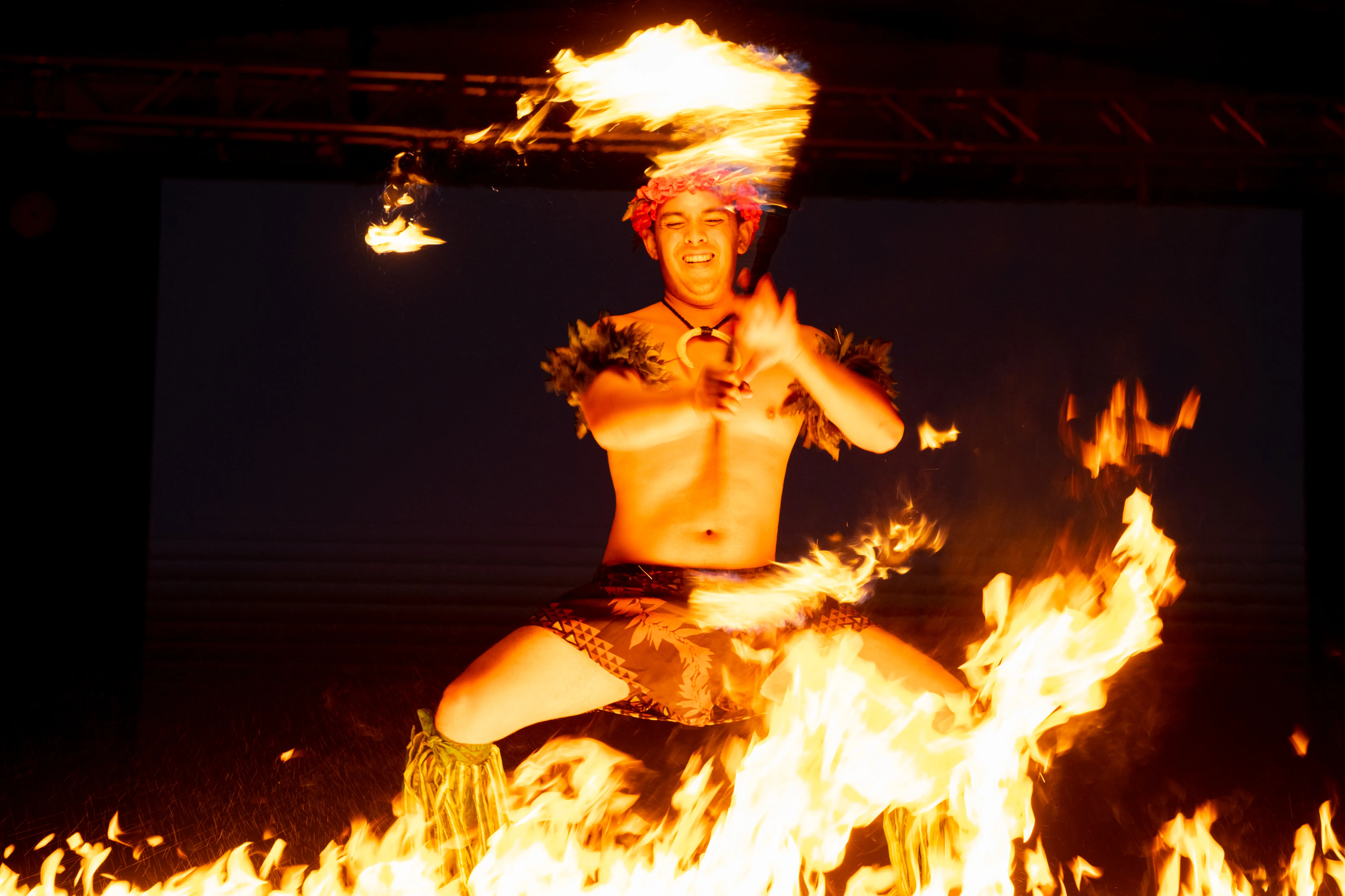 Fire dancer twirls torch surrounded by fire