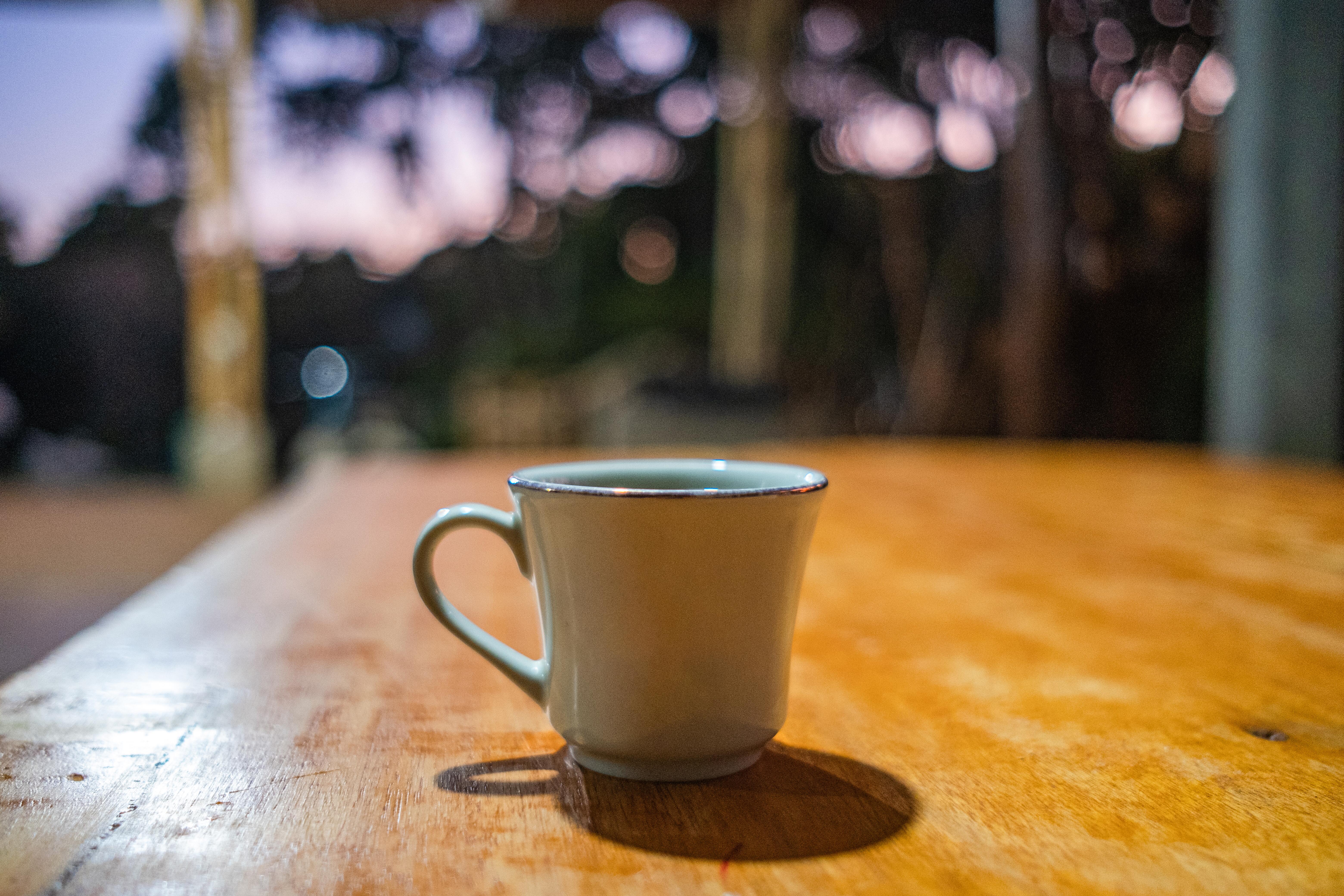 Closeup image of a cup of coffee sitting on a counter in a rustic-looking setting.