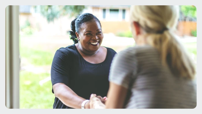 Women smiling and shaking hands with her neighbor