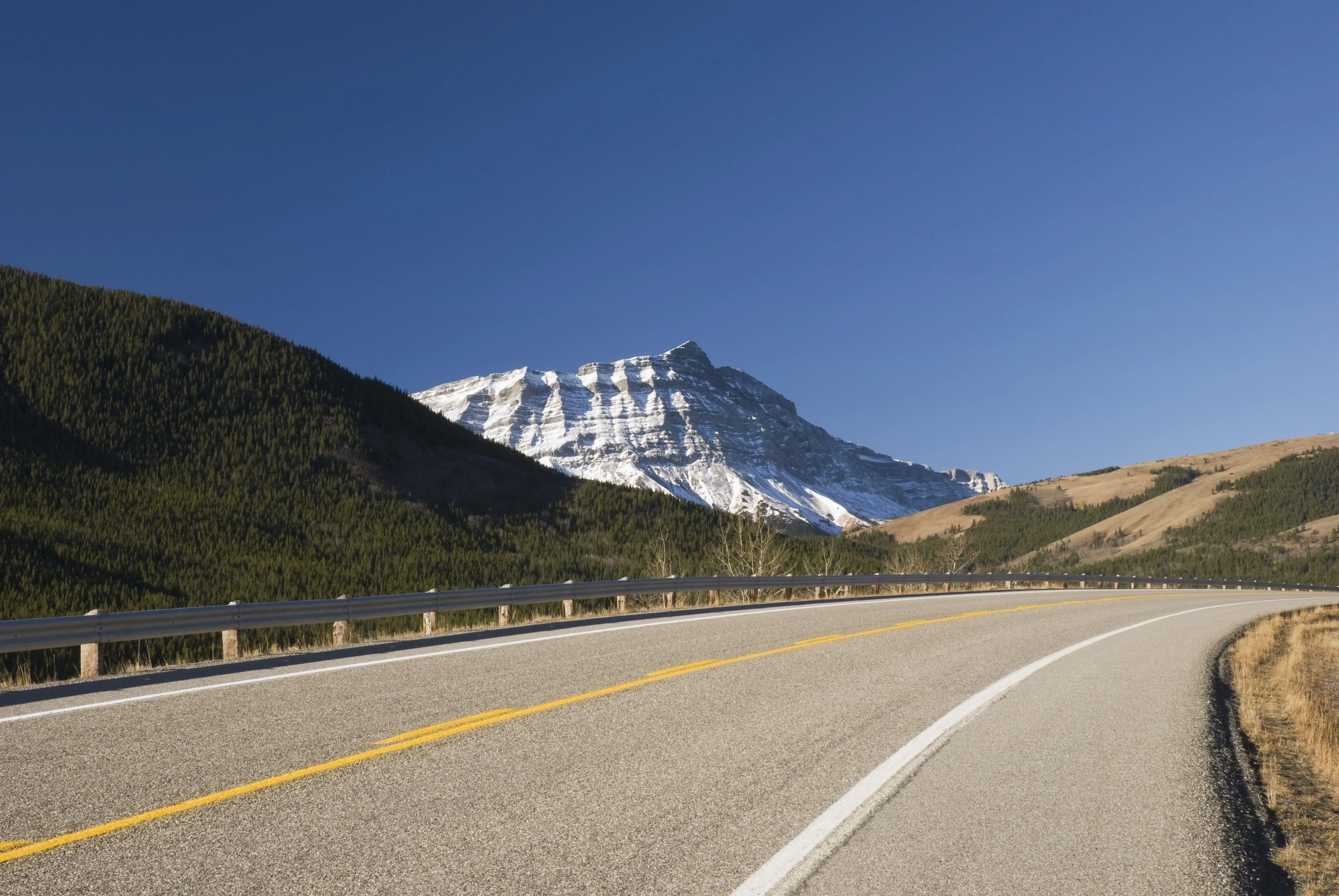 Outdoor image of highway road going past mountains in Canada.