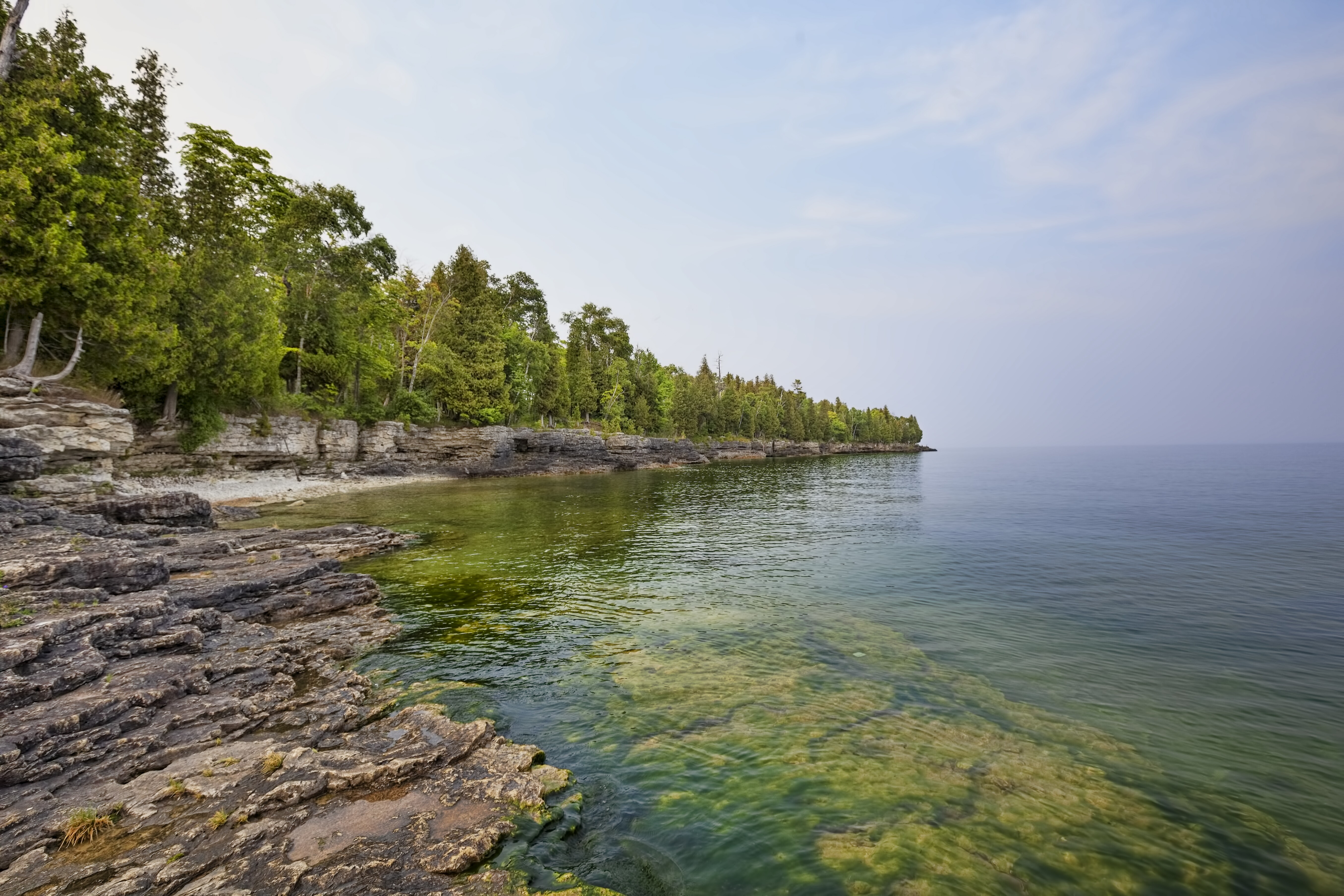 Image of a park featuring underwater caves, hiking trails & limestone cliffs along scenic Lake Michigan.