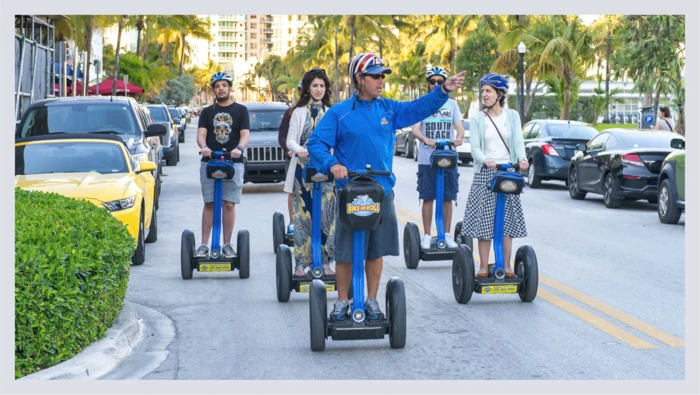 A group of people ride on the street on segways during a city segway tour.