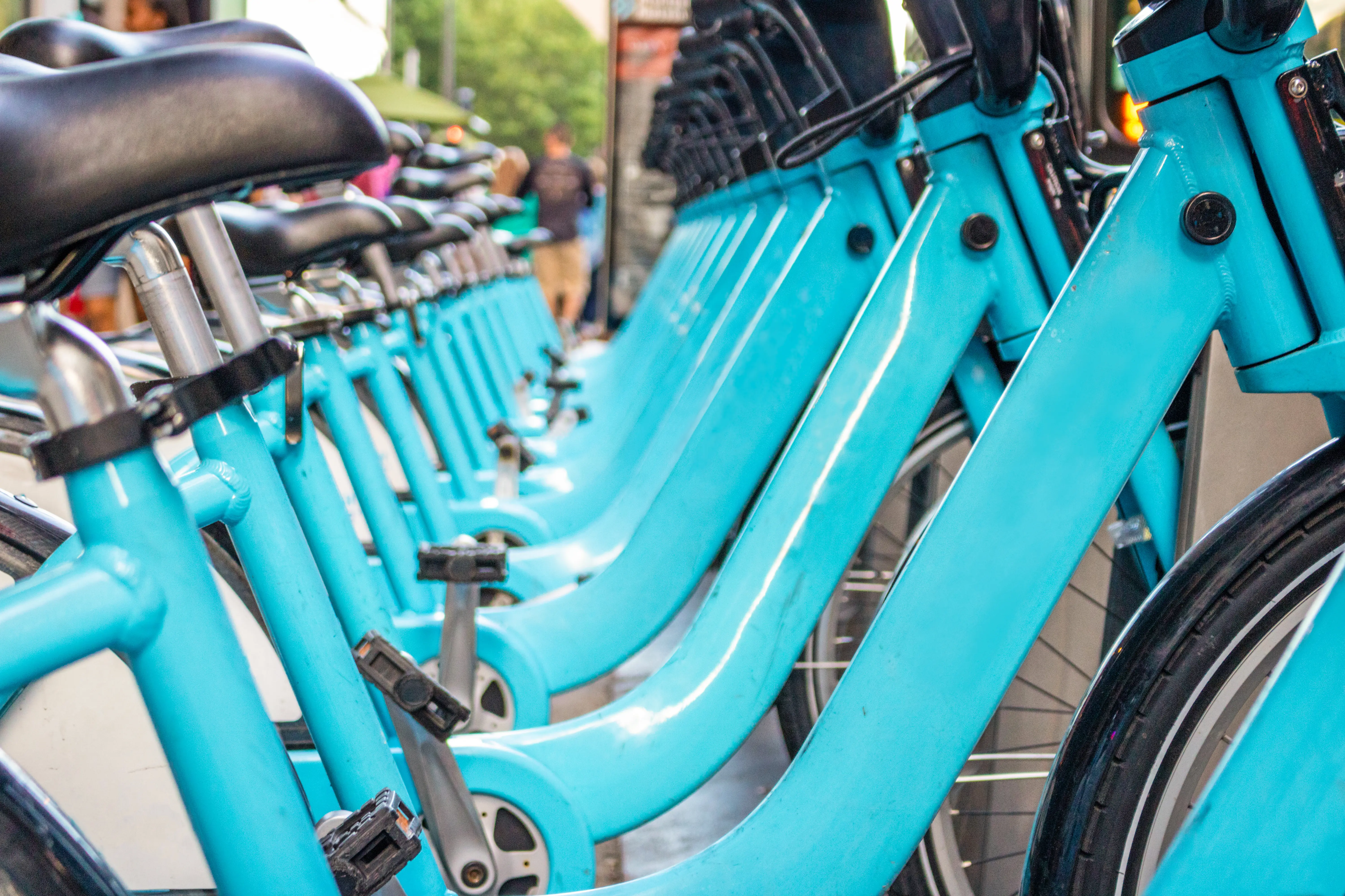 Blue city bikes lined up at a bike station on the sidewalk