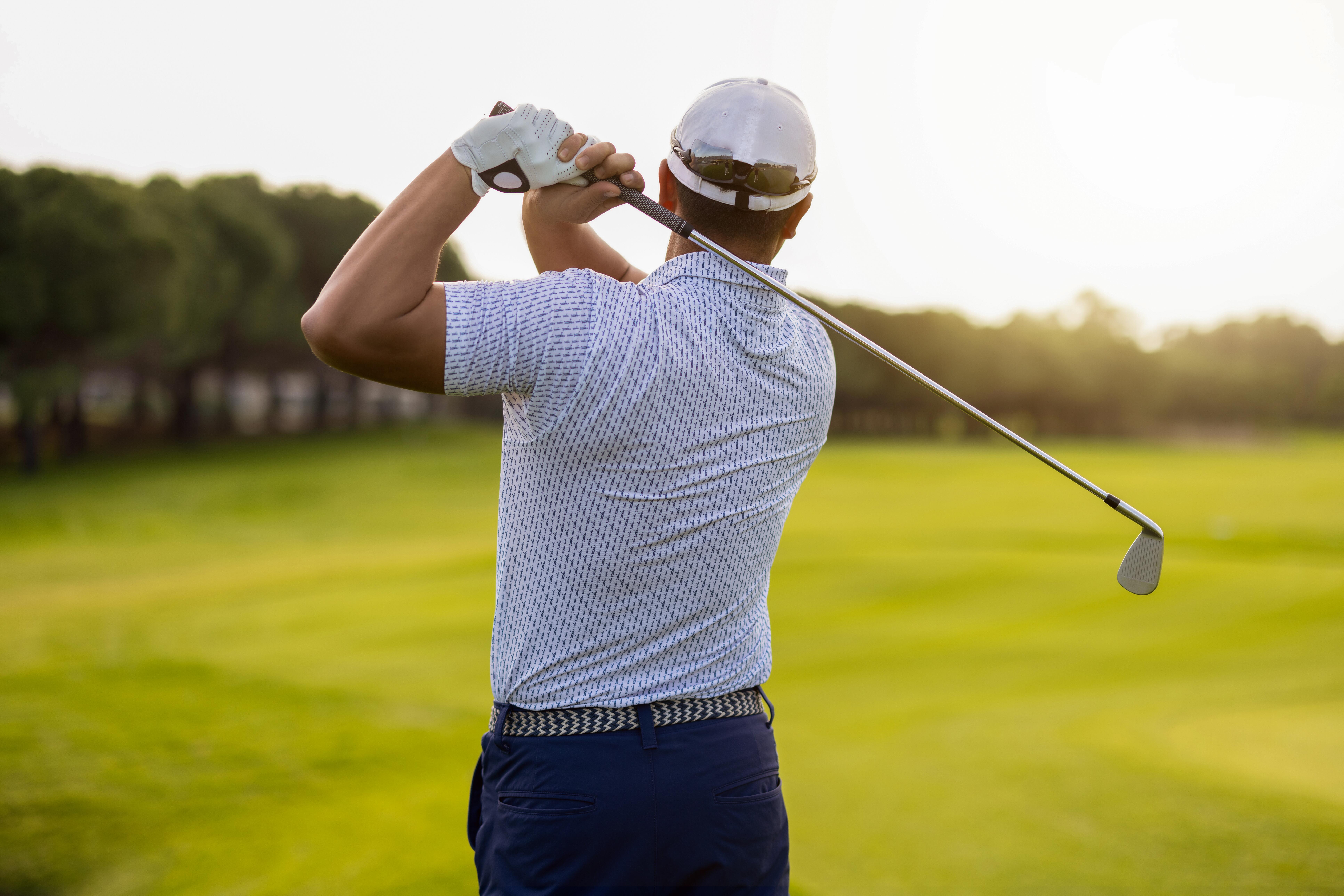 Image of a man golfing as the sun shines down.