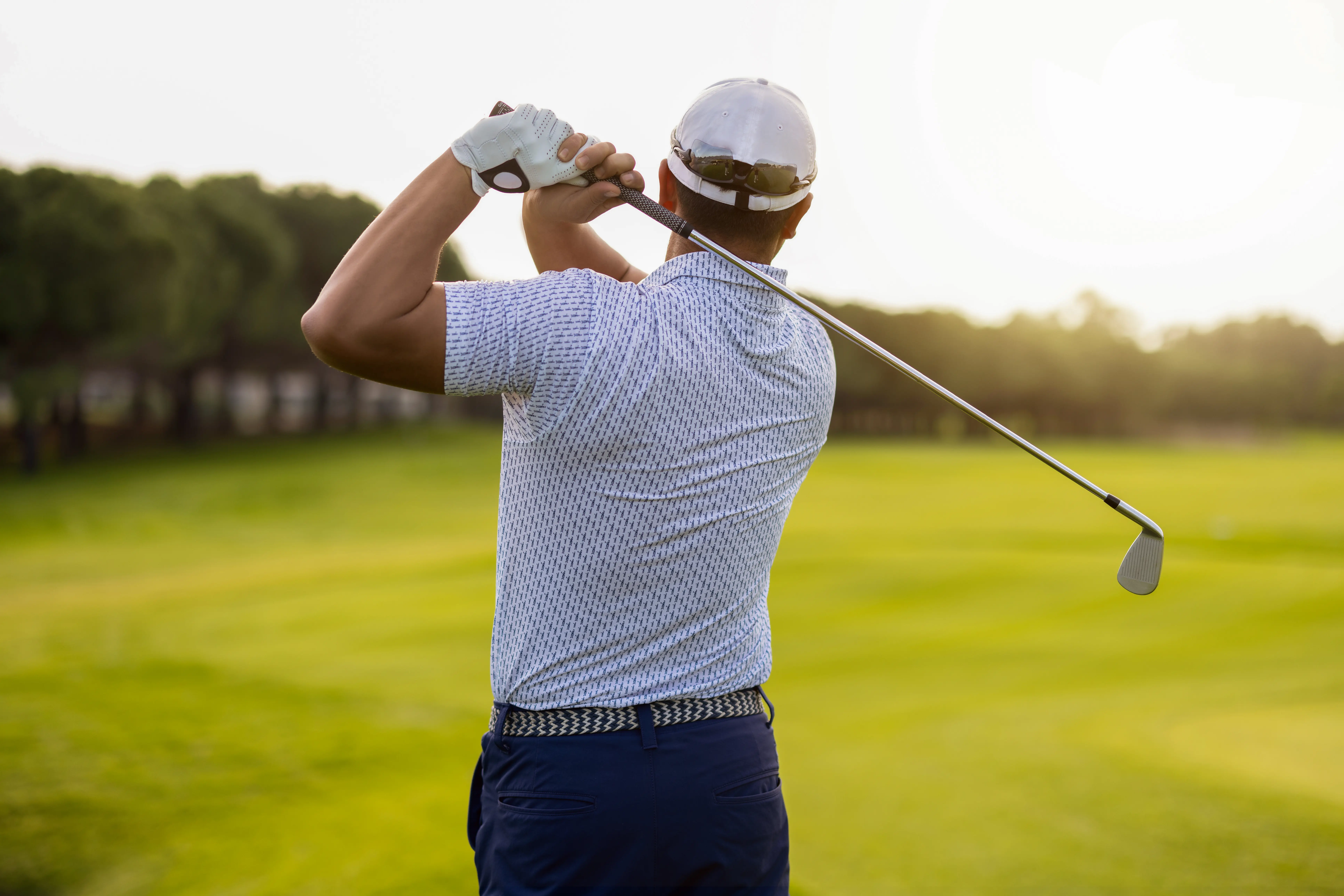 Image of a man golfing as the sun shines down.