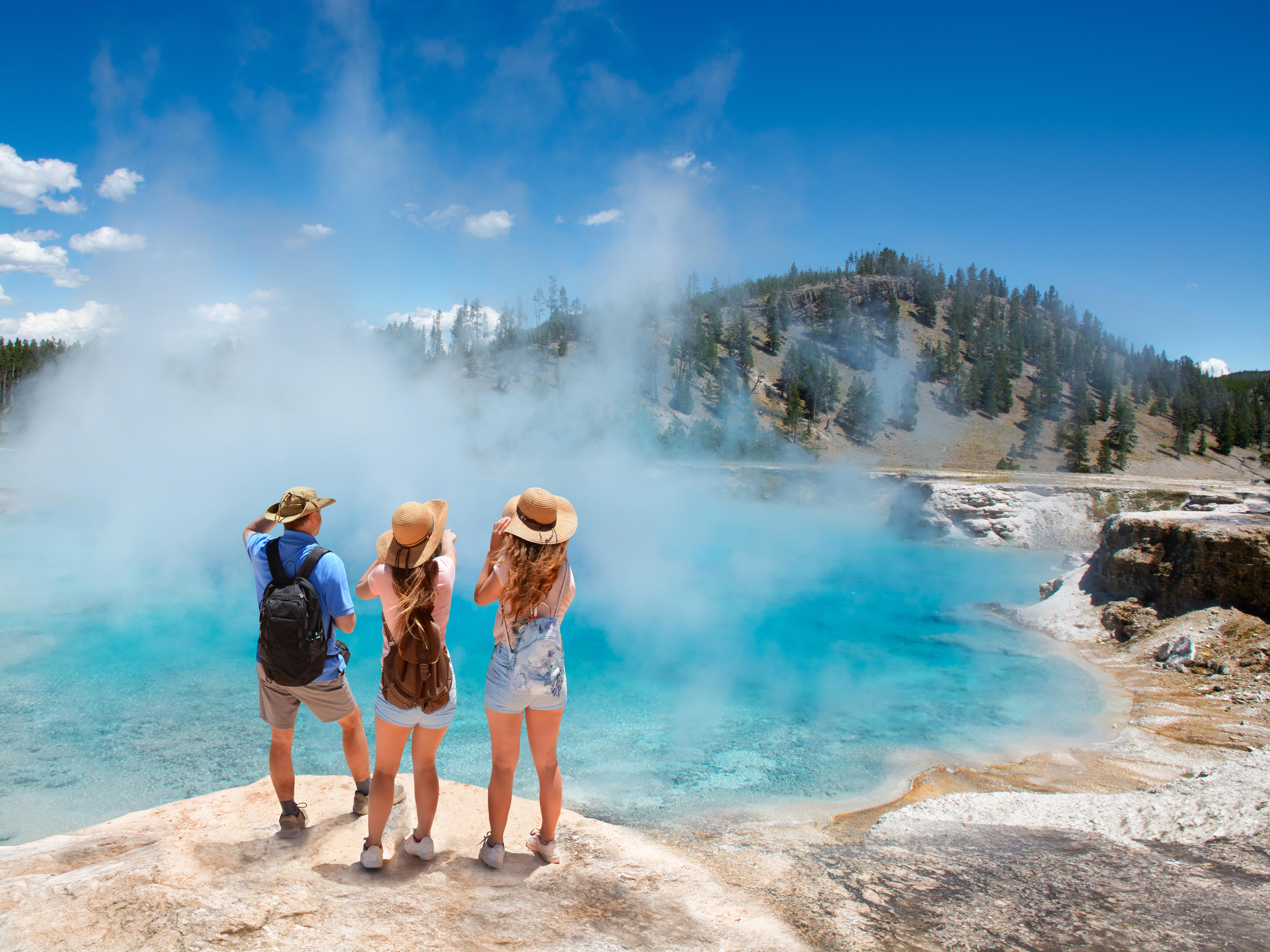 Family or friends enjoying beautiful view of Excelsior Geyser from the Midway Basin in Yellowstone National Park on a sunny day, Wyoming, USA