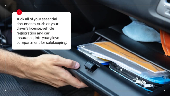 A driver tucking in their essential documents into the glove compartment of their vehicle. 