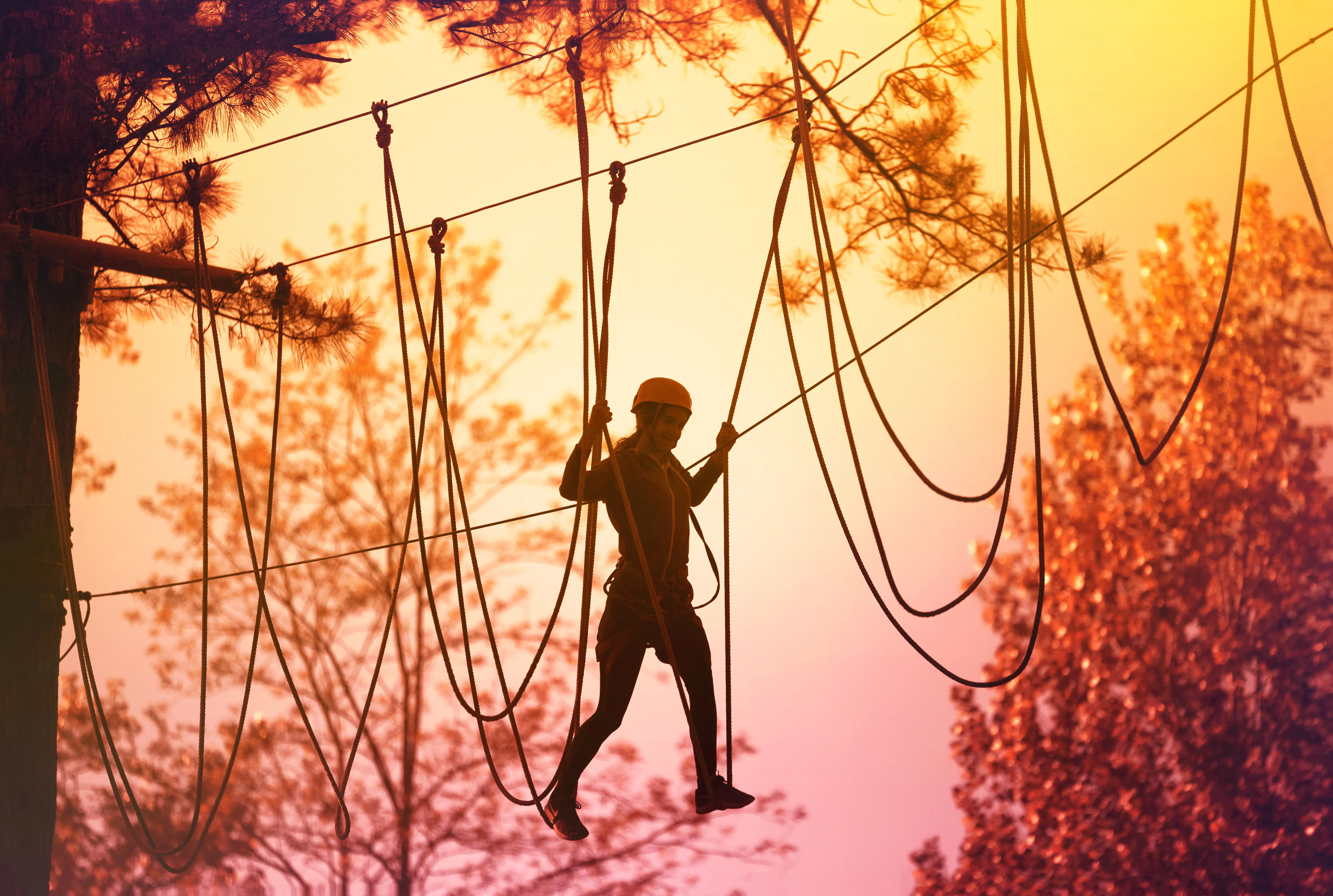 Image of a girl on a rope climbing course at a zipline park.