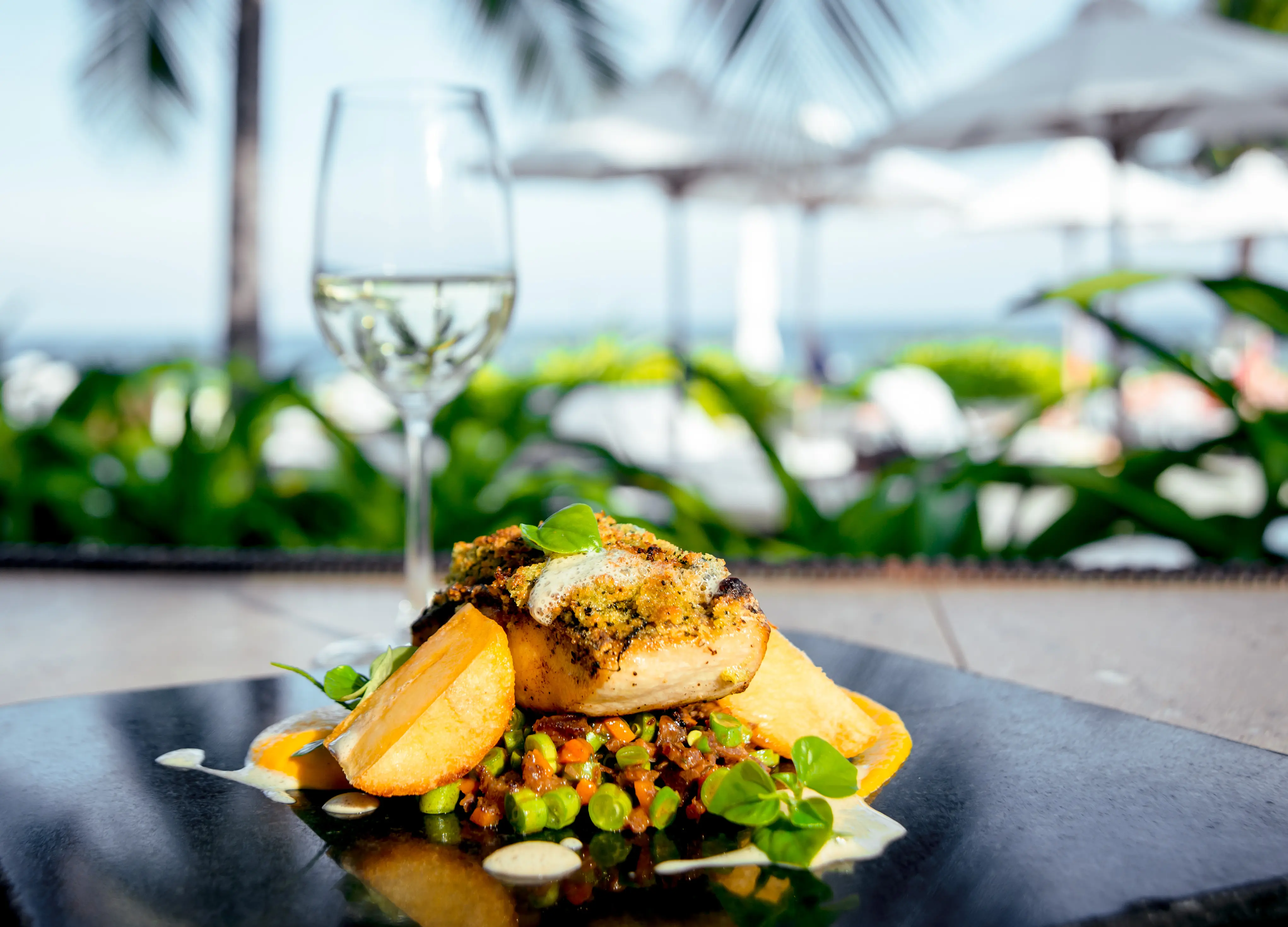 Fried fish with potatoes and salad on a white plate near the beach or sea