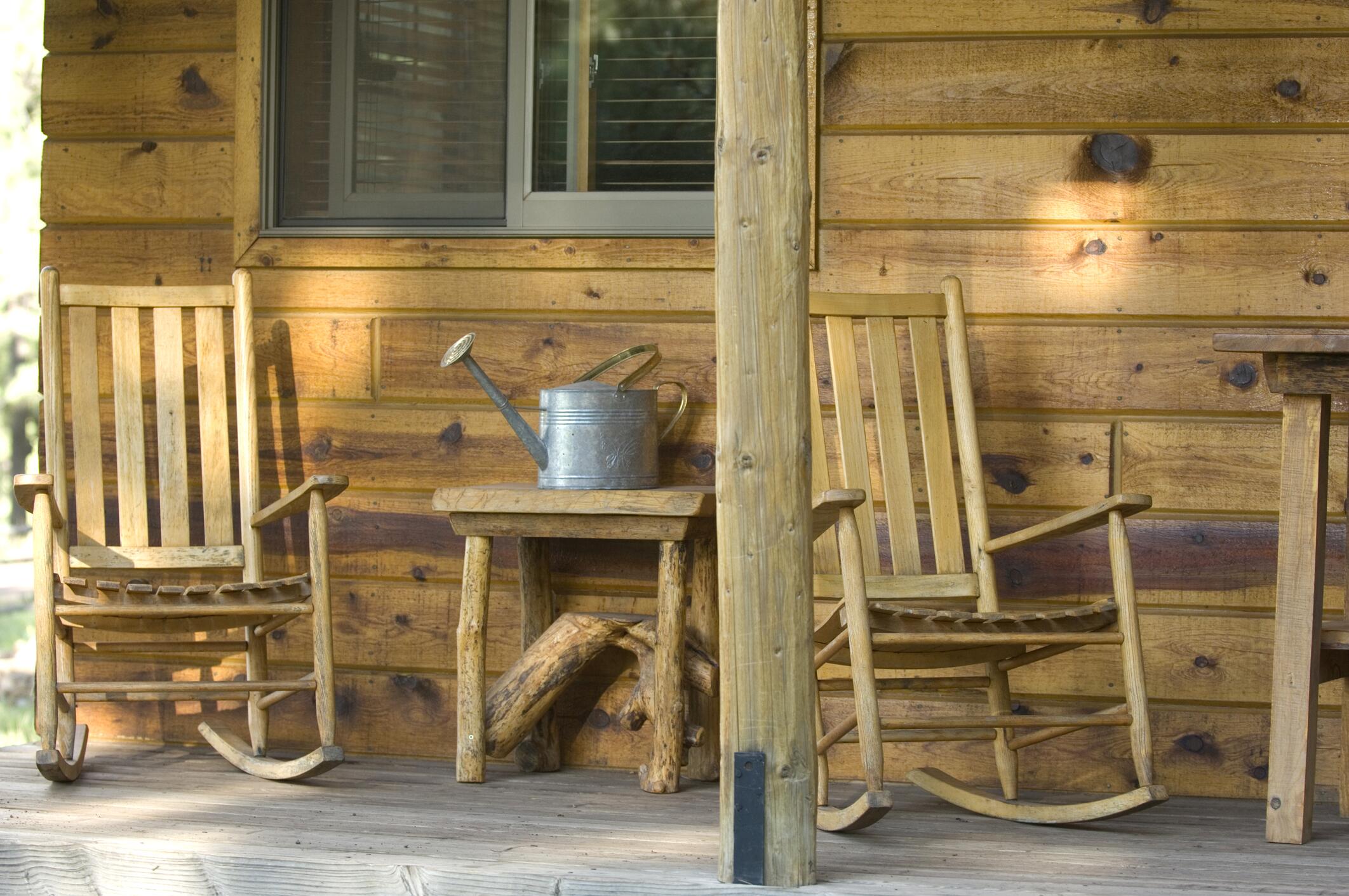 Wooden rocking chairs on the front porch of a rustic cabin.