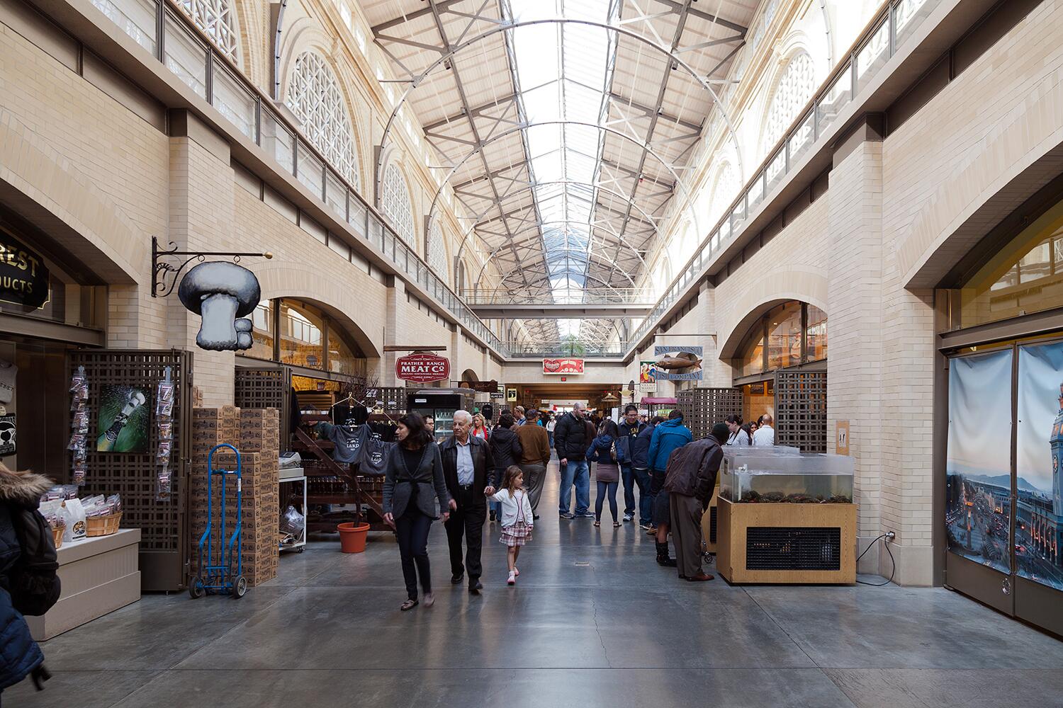 Interior photo of the Ferry Building Marketplace, with people walking and looking at the stores.