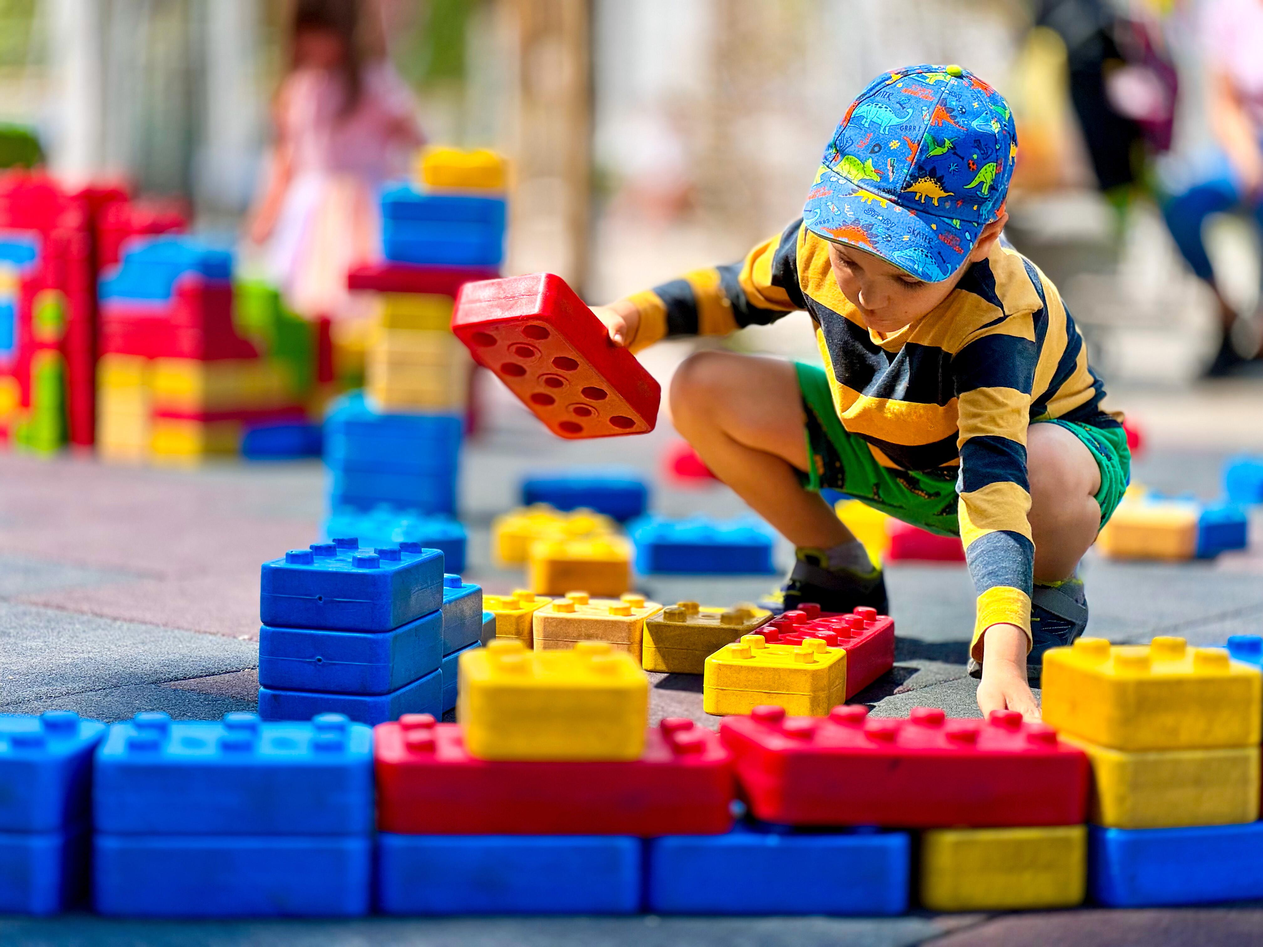 A young boy focused on arranging large, colorful building connecting blocks