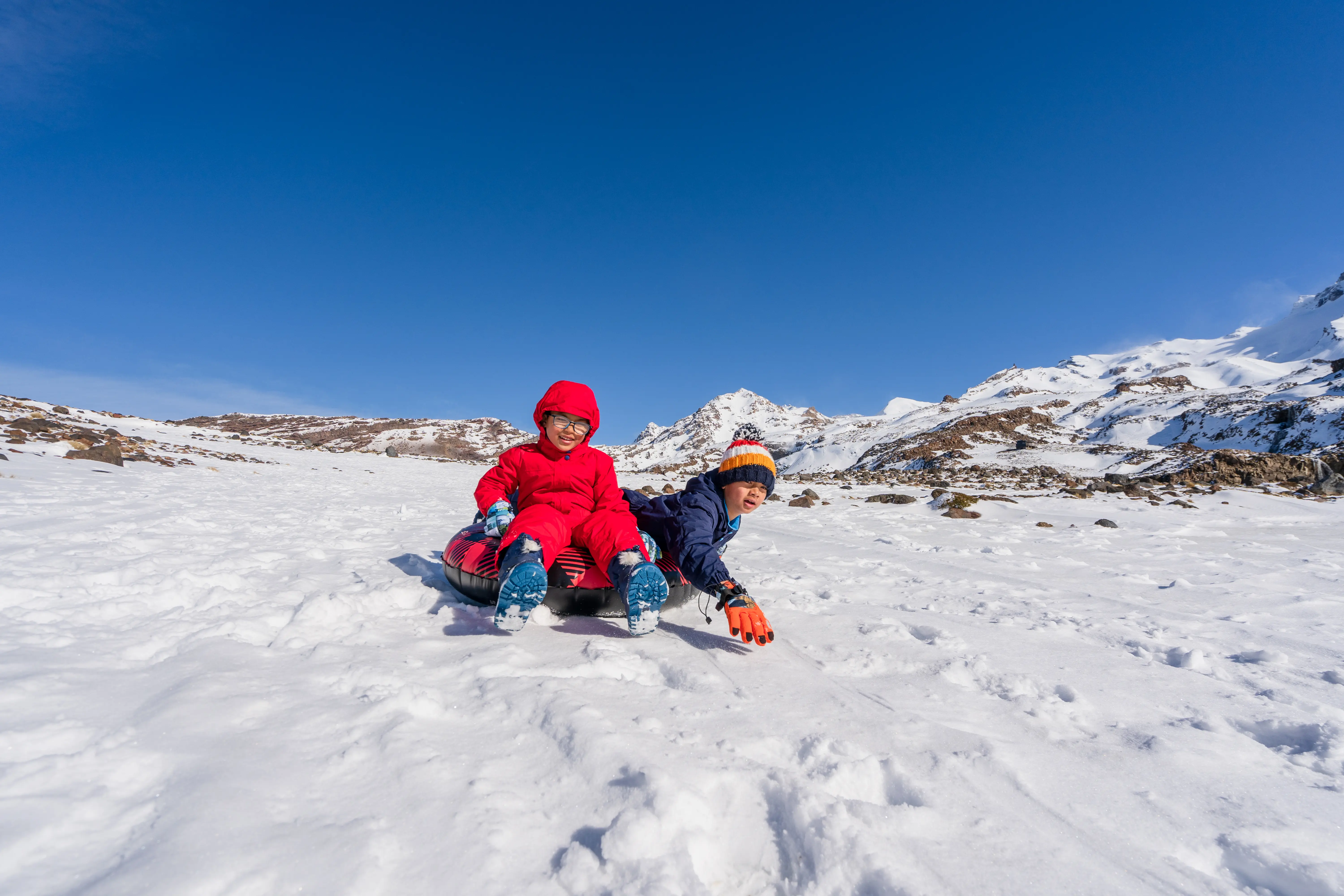 Image of children snow tubing down a snowy hill.