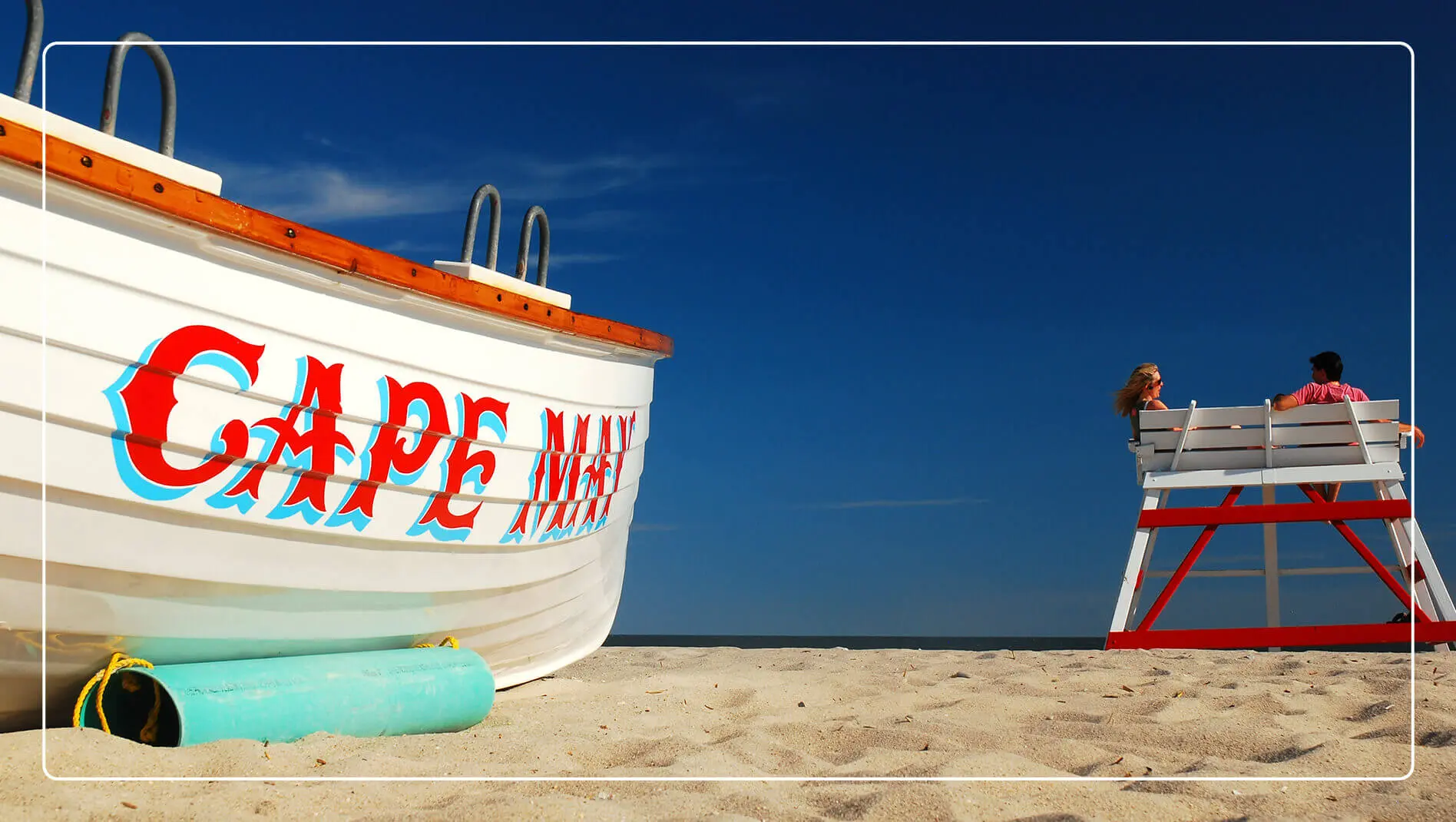 A tourist photo opportunity with a boat and lifeguard chair on Cape May Beach.