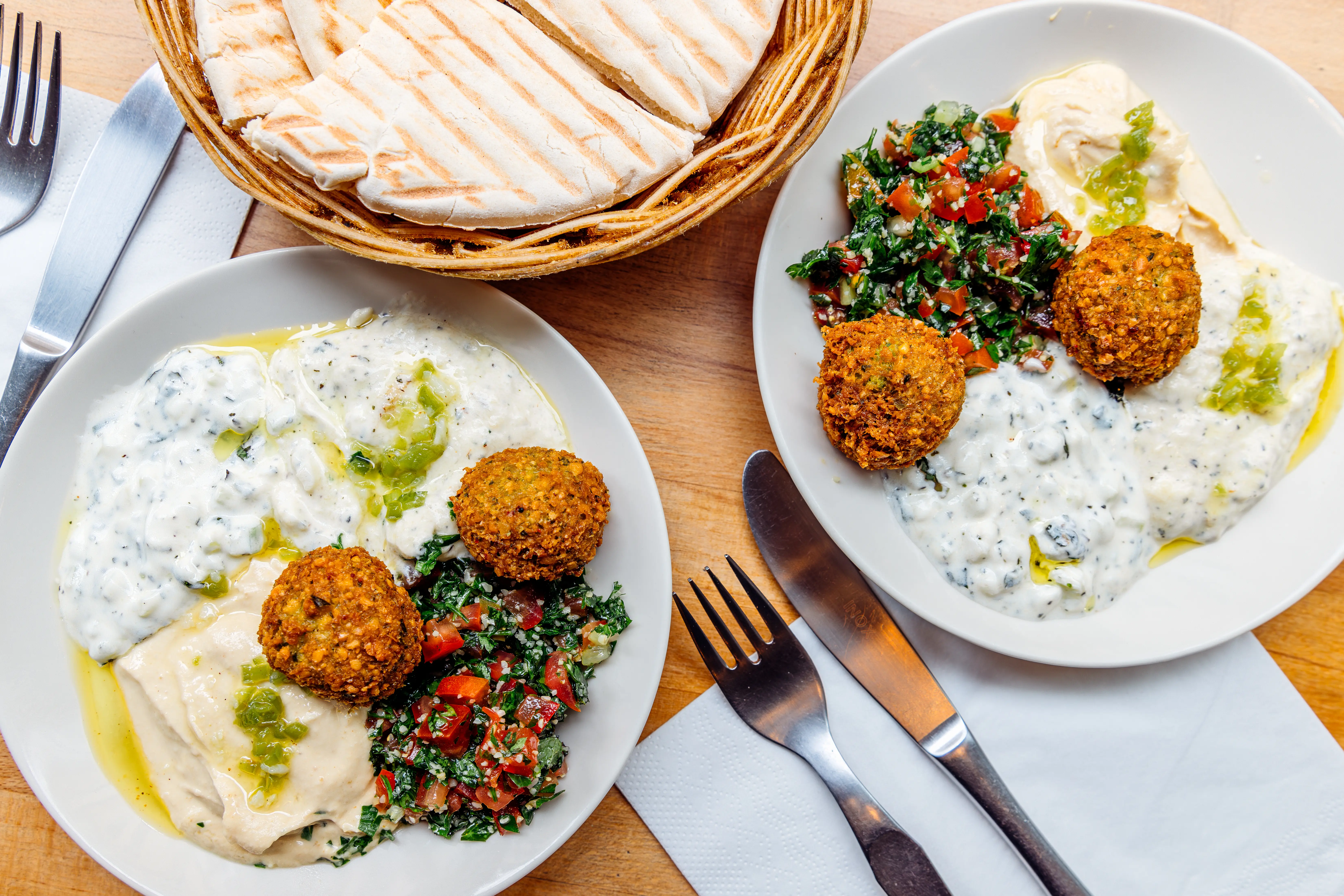 Image of a dish of hummus, served with falafel and pita bread.