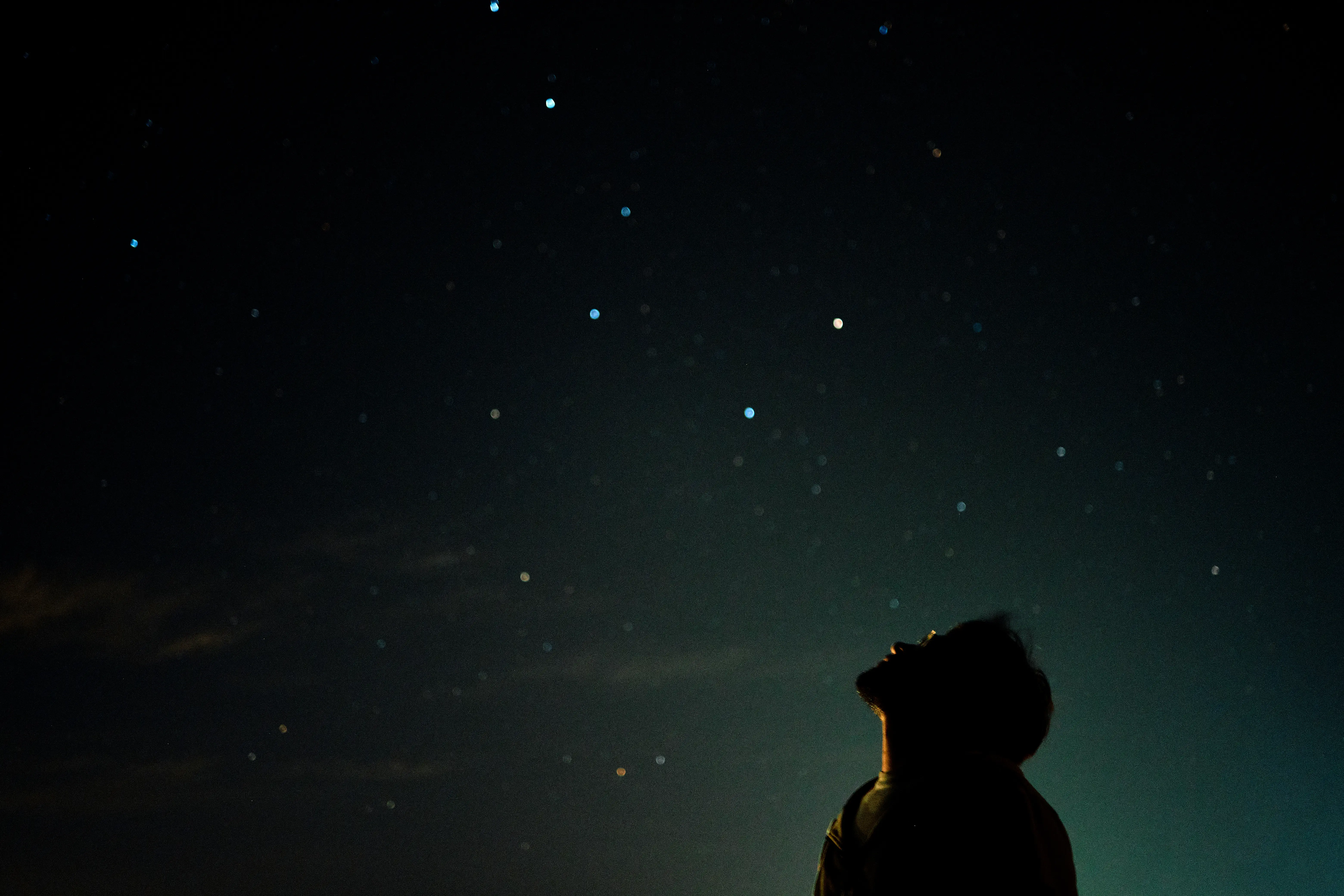 Image of a man looking upwards at the stary night sky.