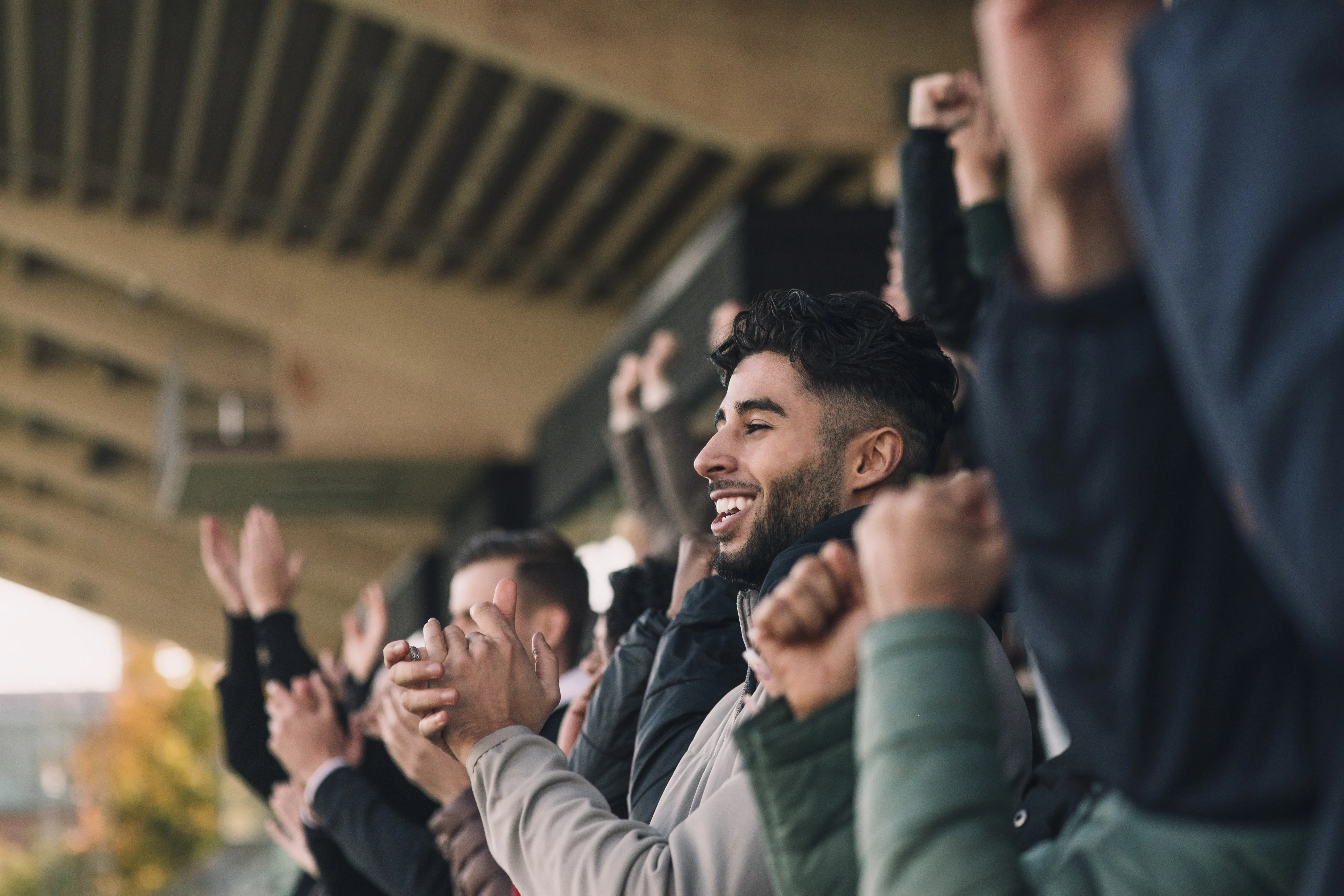 Image of a man standing and applauding in the crowd at a sports arena.