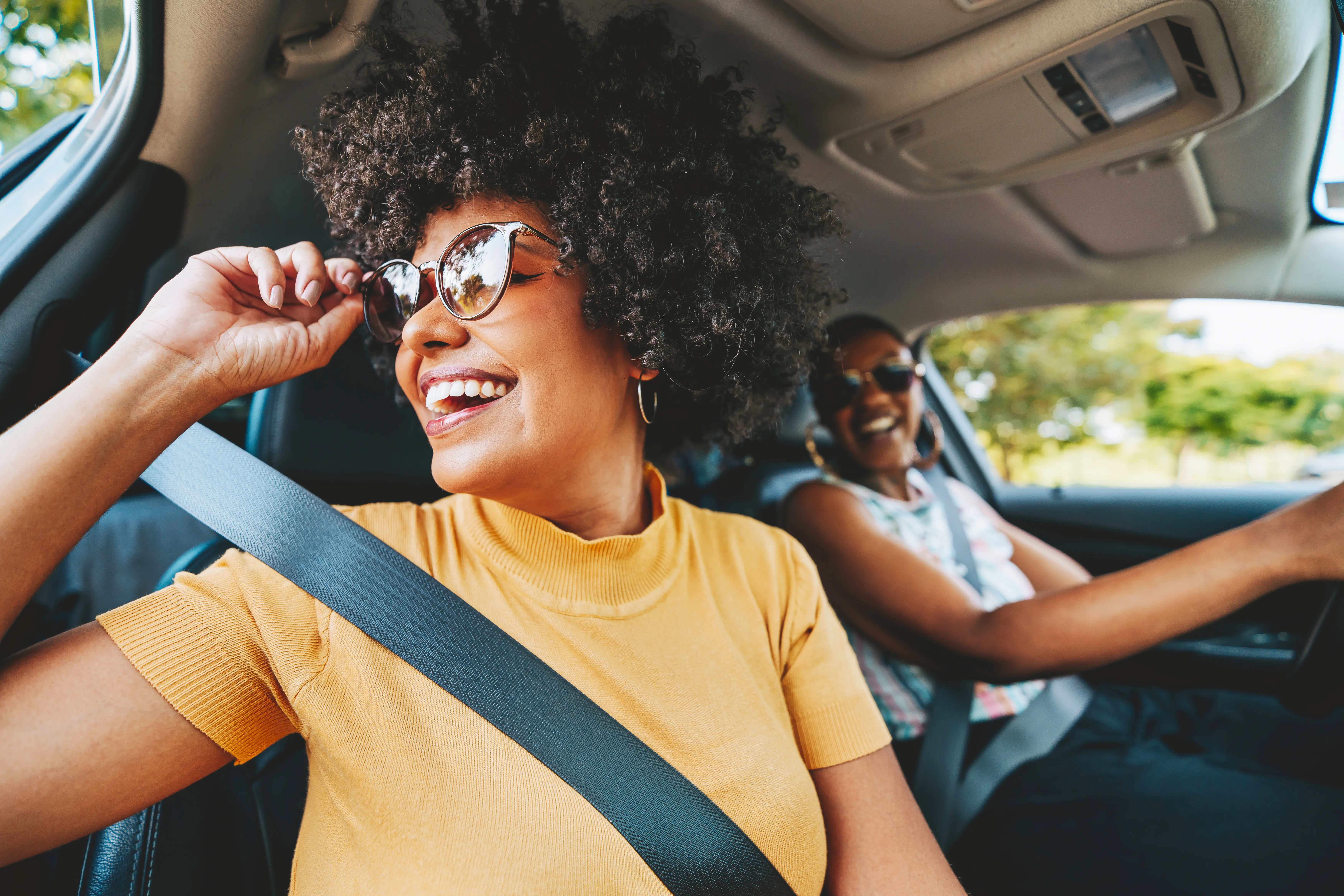 Two black women smiling, traveling by car to go sightseeing