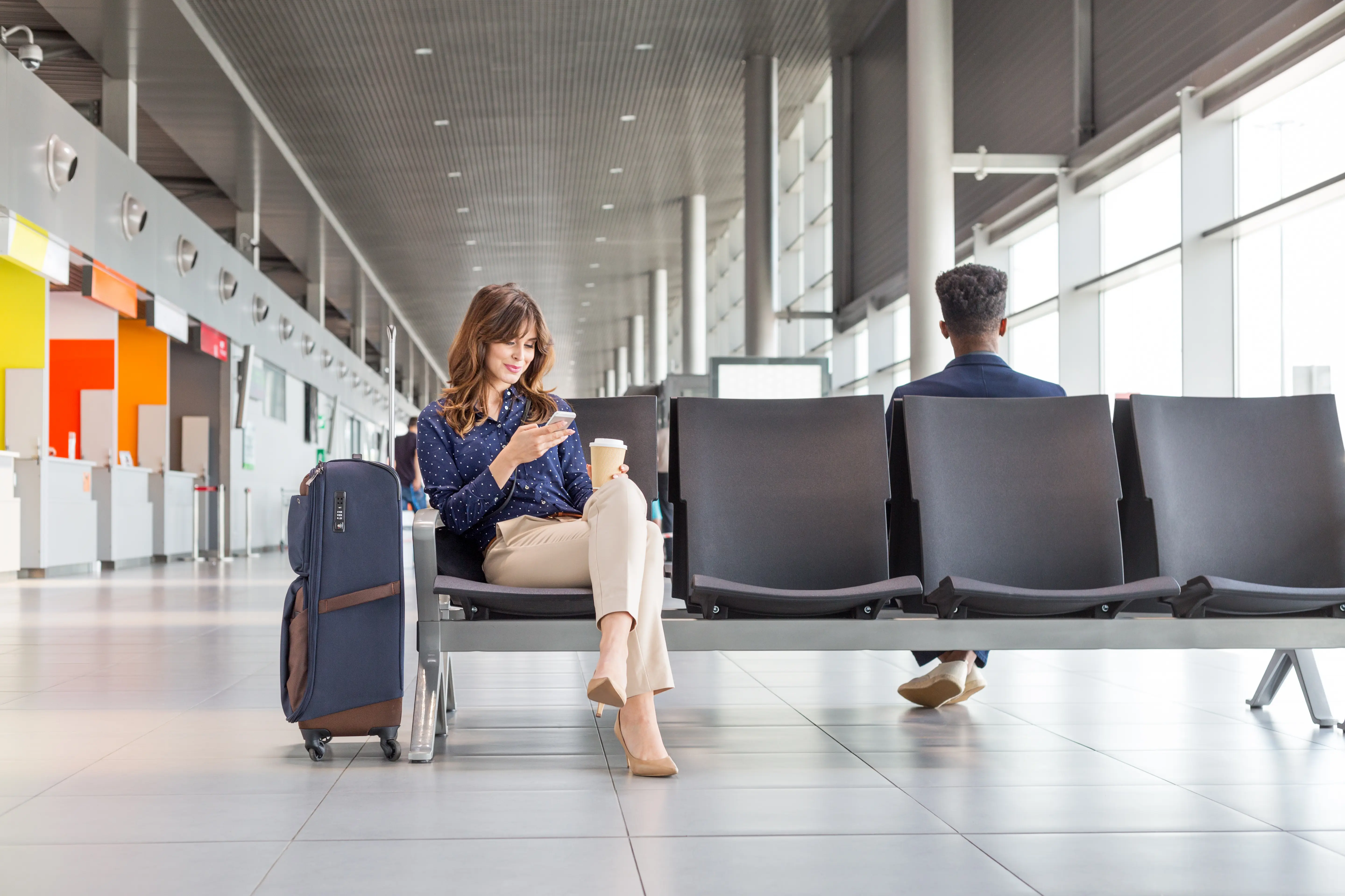 Woman in airport waiting area with suitcase