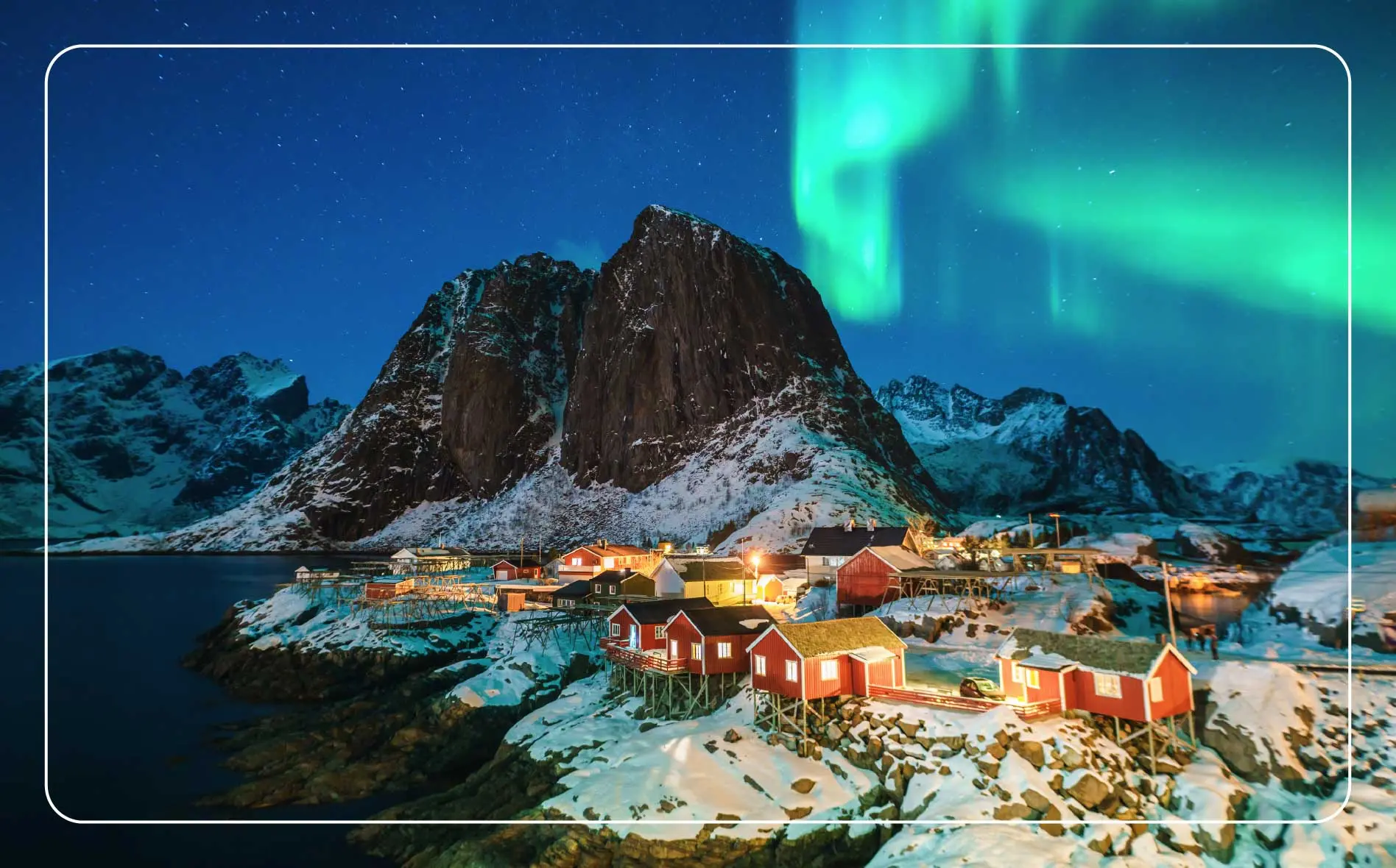 A village in the Lofoten Islands in Norway with the Northern Lights illuminating the night sky.