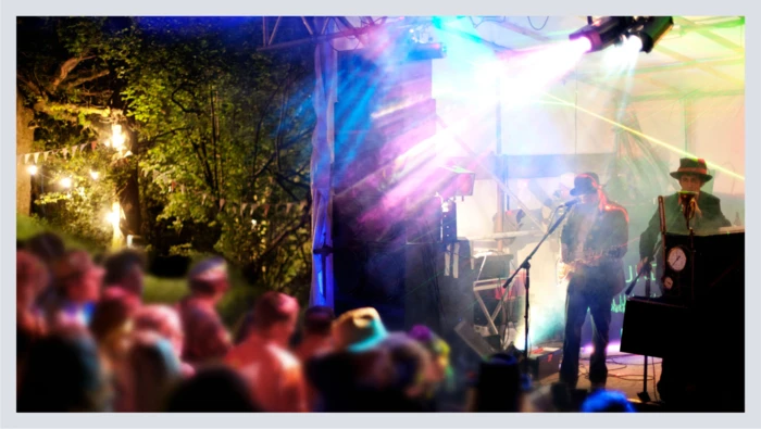 A crowd watches a band perform a live music event outside. 