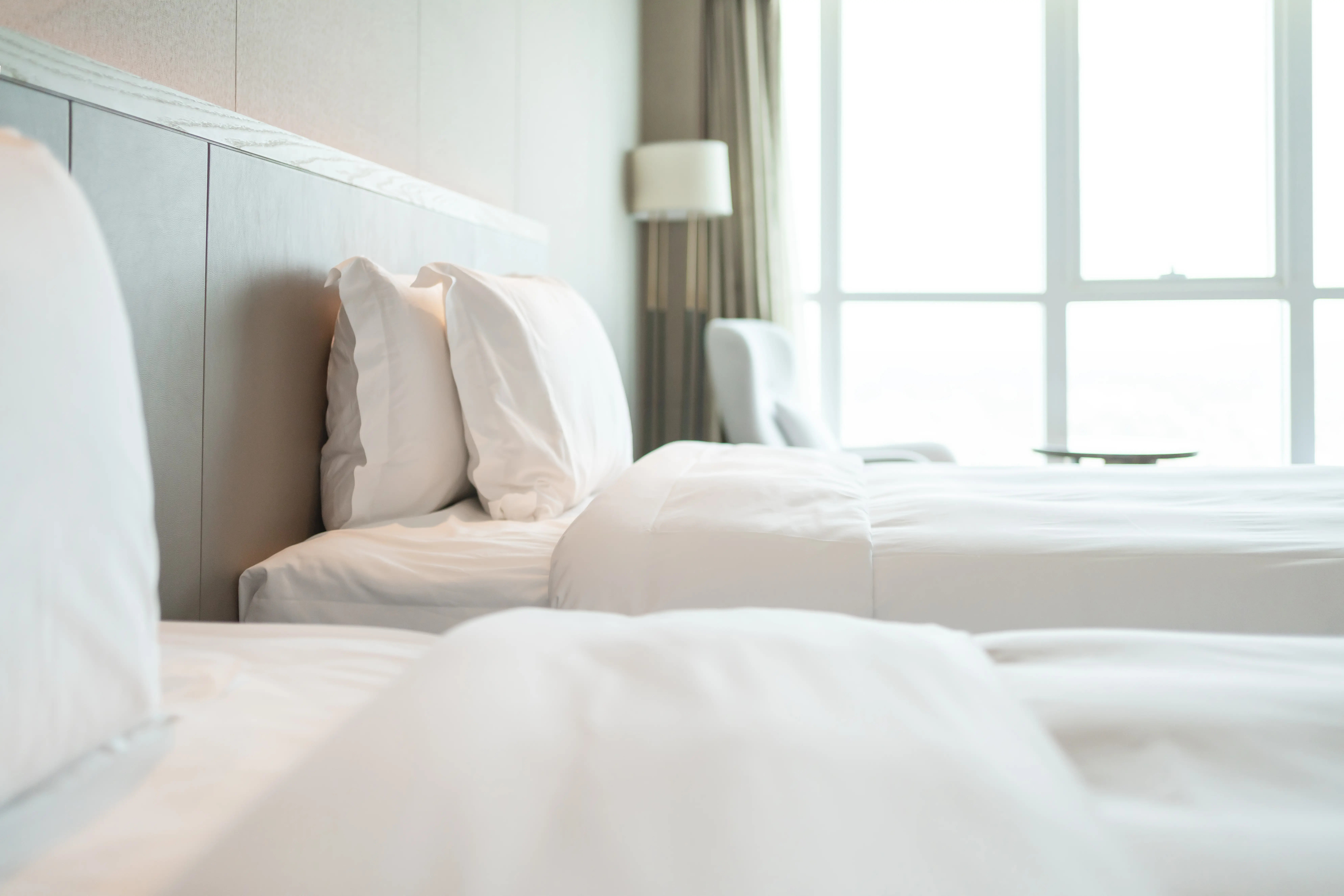 Closeup image of two beds in a sunny hotel room.